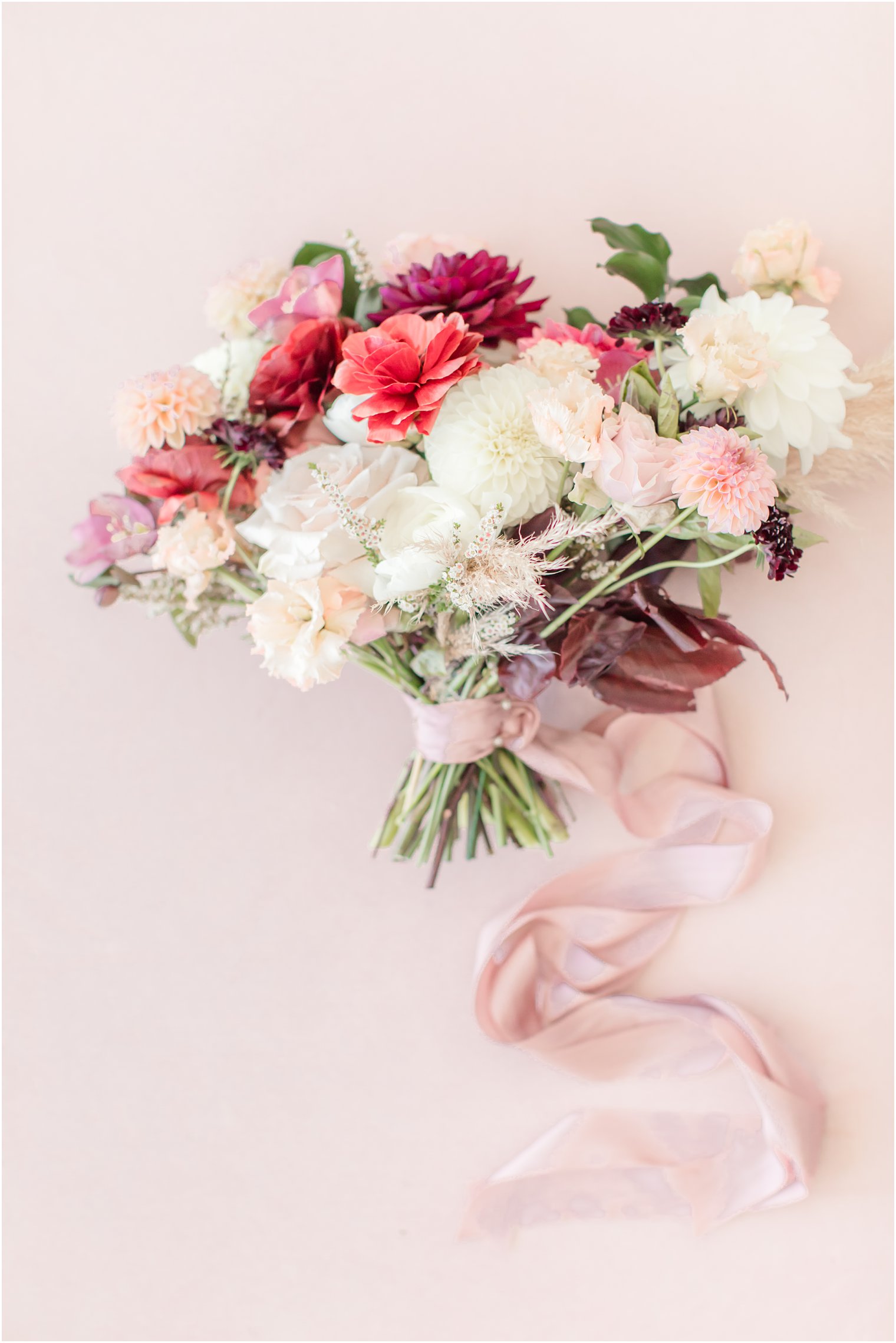 fall wedding bouquet with pink ribbon and red and white flowers