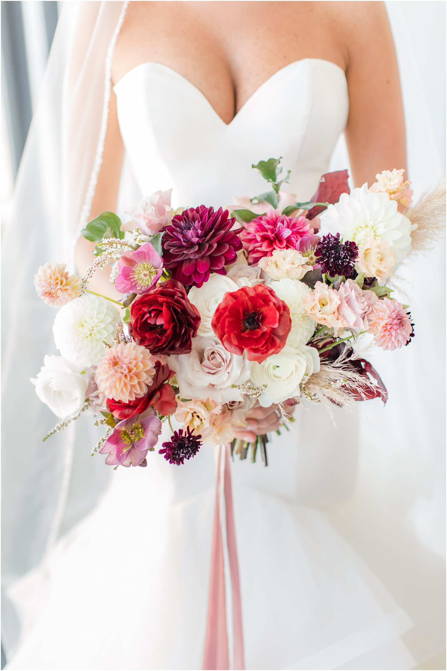 fall wedding bouquet with red and pink flowers and pink ribbon by Cassandra Shah