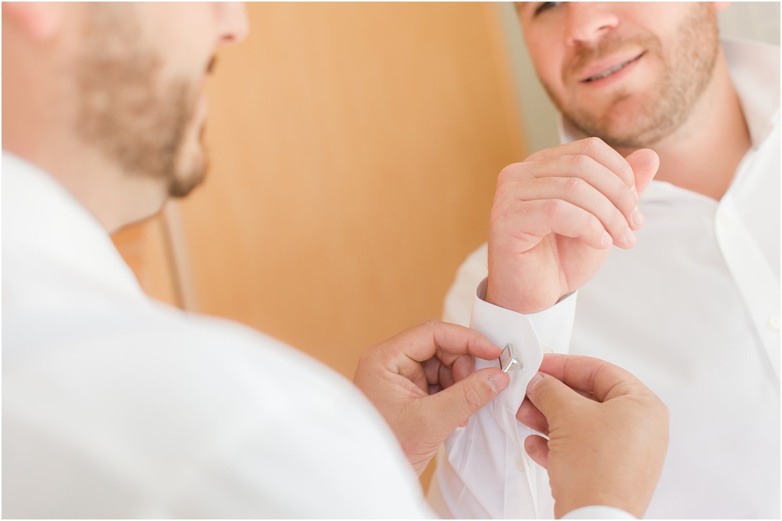 groomsman adjusts groom's cufflinks before NJ wedding