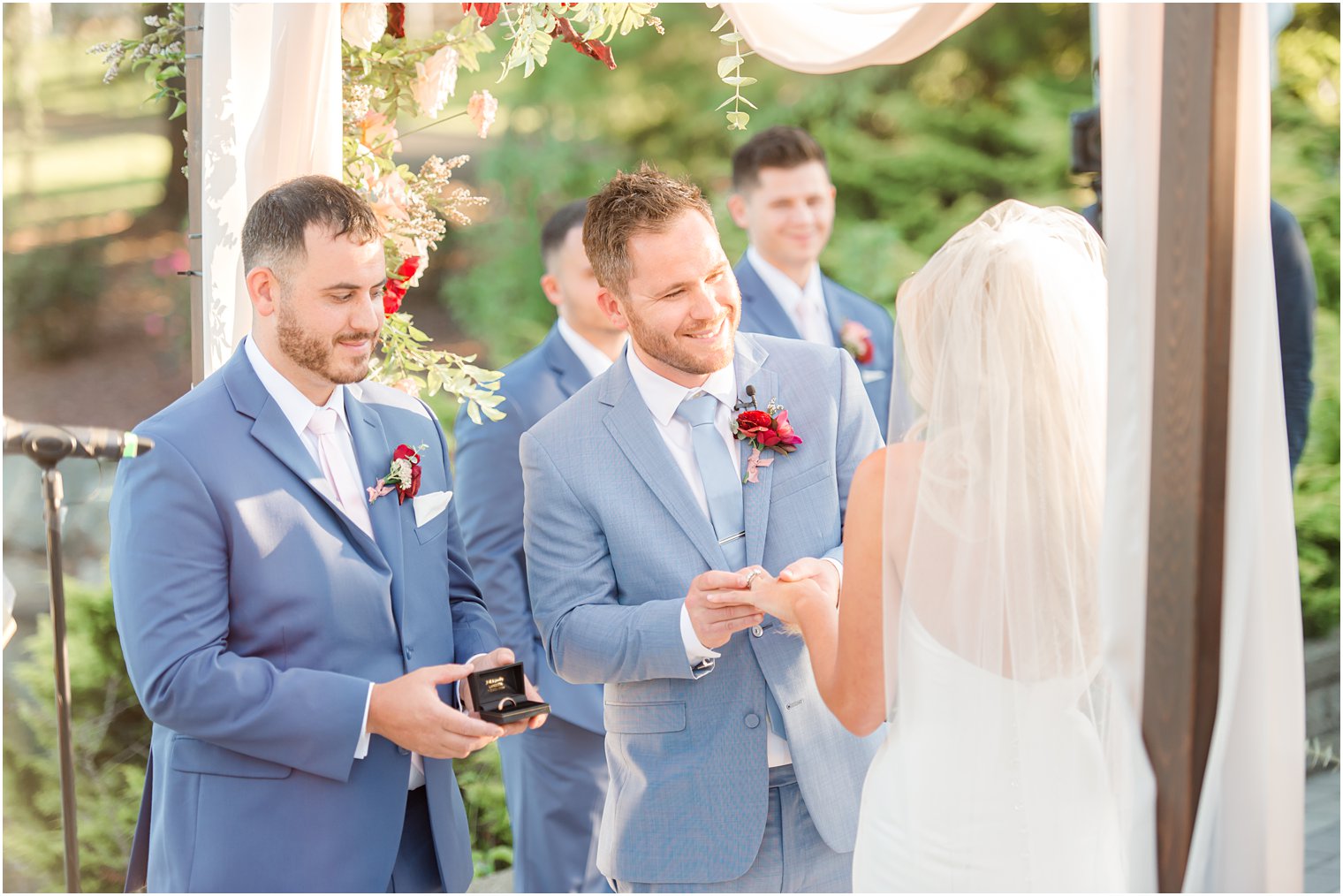 groom gives bride ring during wedding ceremony at Windows on the Water at Frogbridge