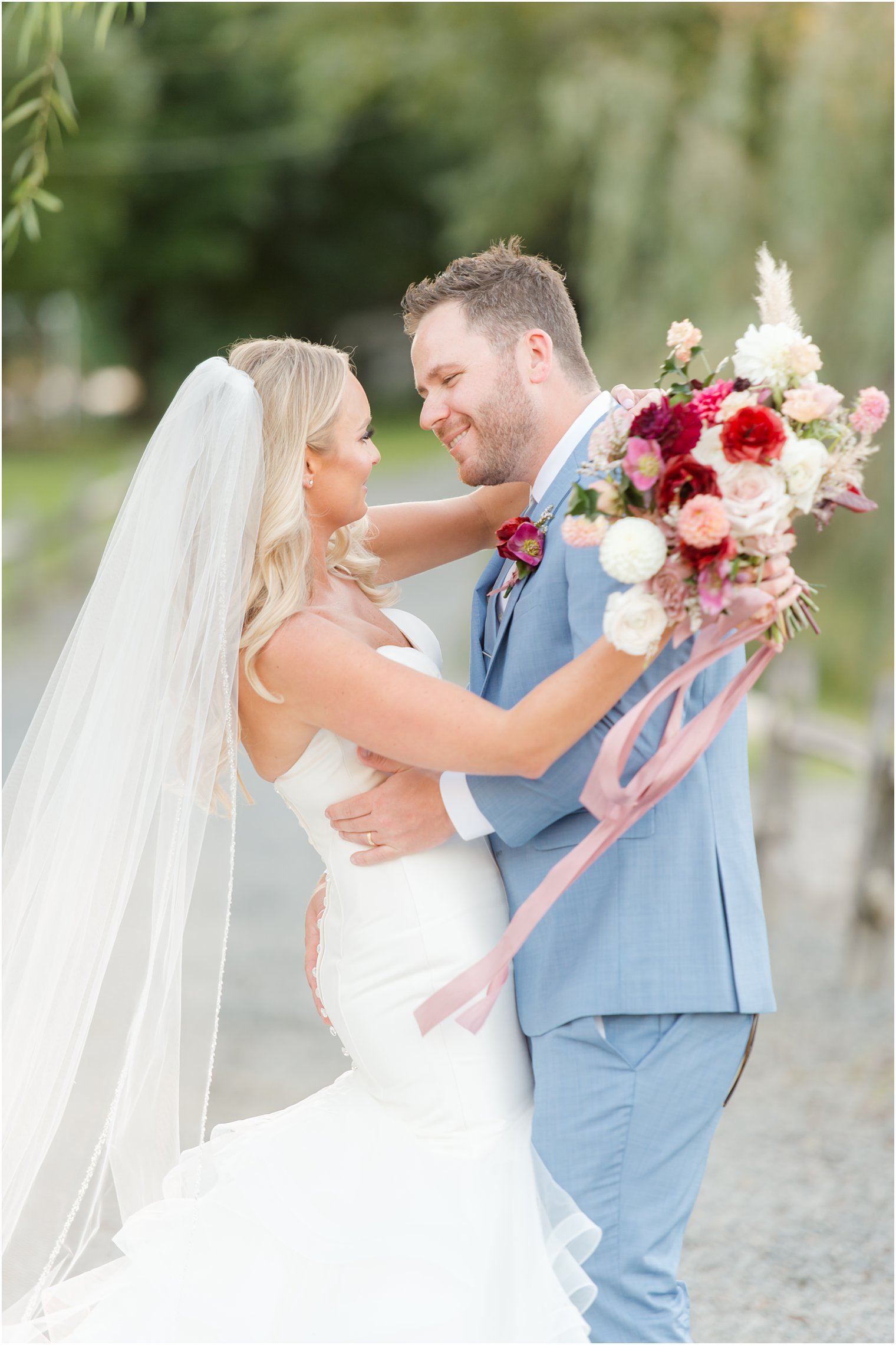 bride and groom laugh during New Jersey wedding portraits with veil behind bride