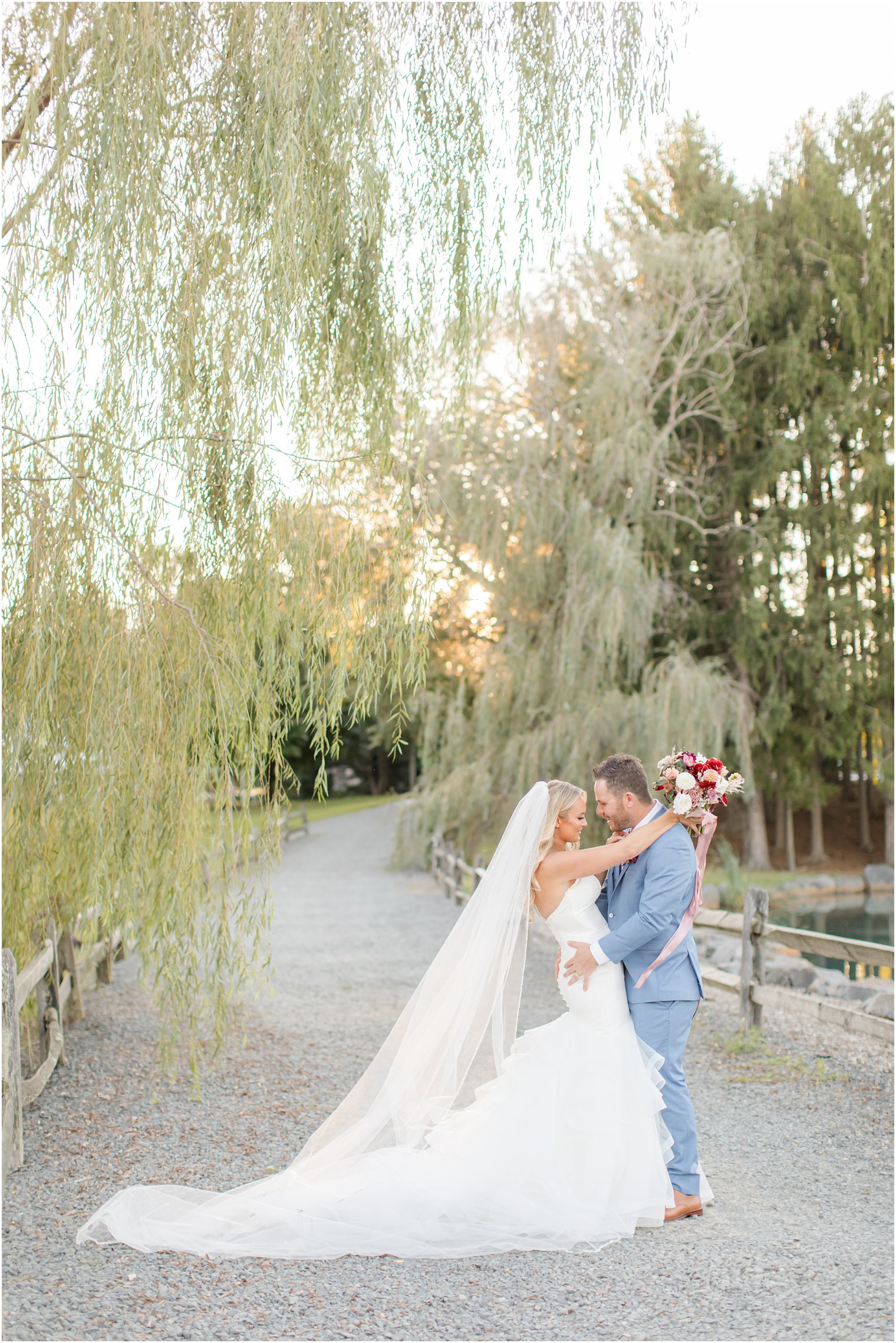 groom holds bride by hip at sunset during Windows on the Water at Frogbridge wedding photos