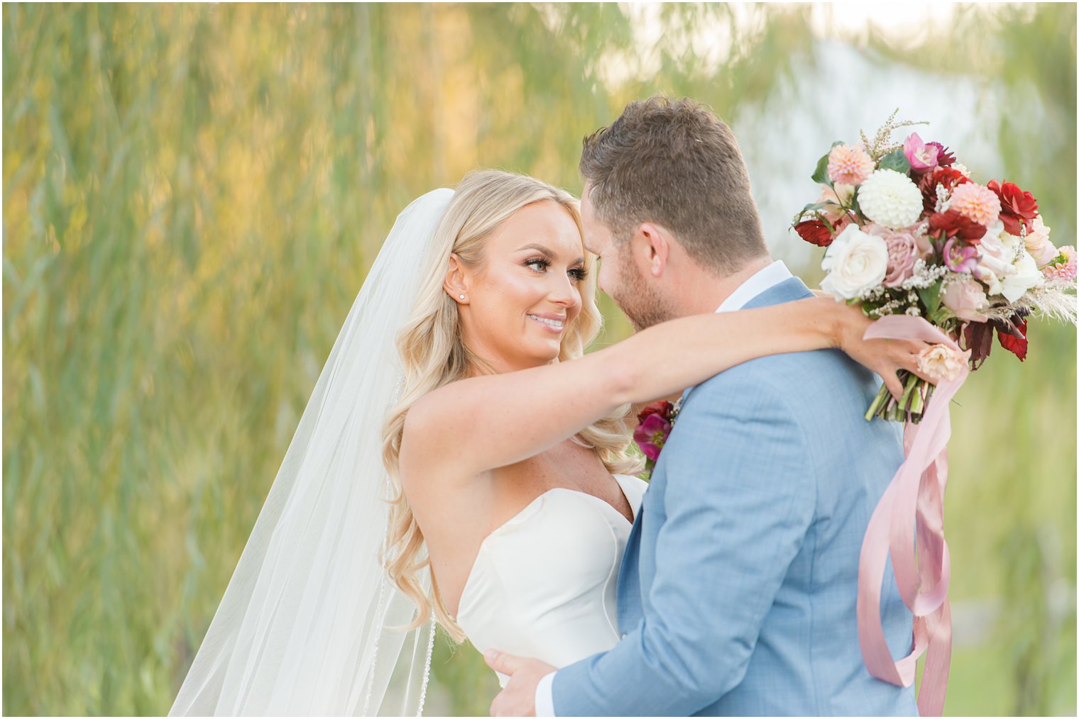 bride holds bouquet behind groom's head during NJ wedding portraits 