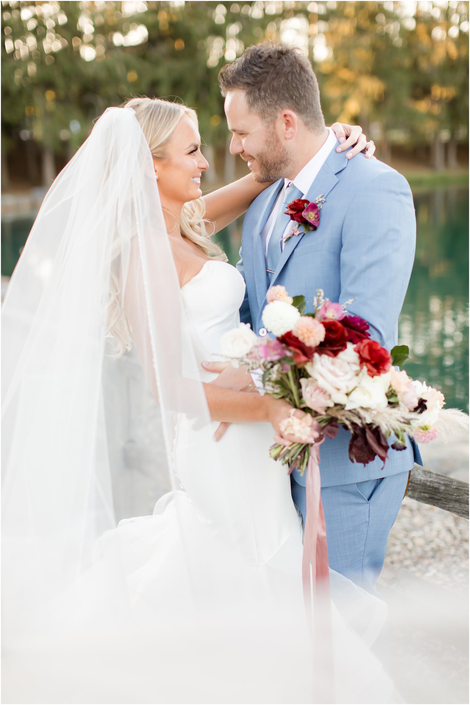 bride holds onto groom's neck during wedding portraits in New Jersey