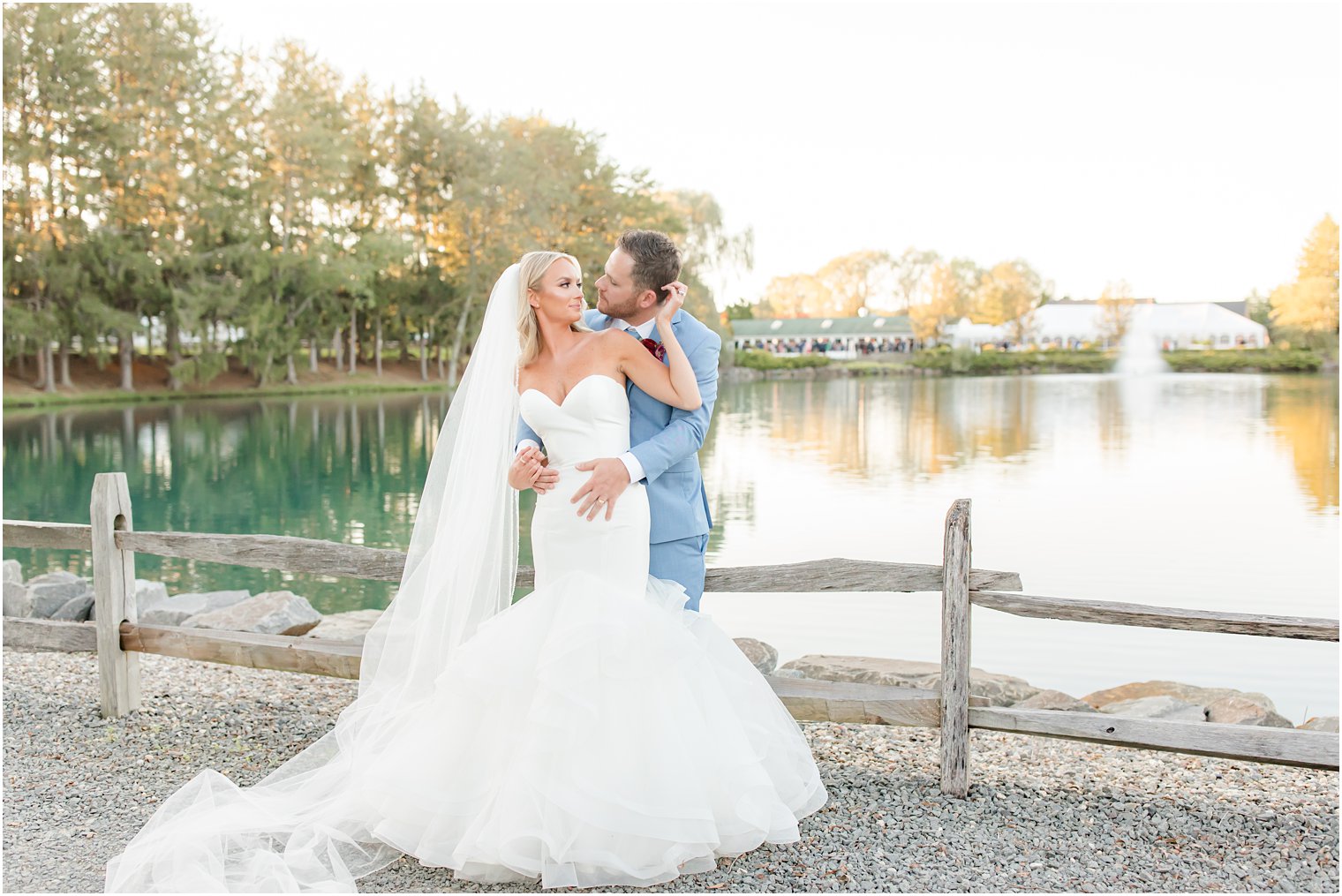 bride holds groom's head behind her during Windows on the Water at Frogbridge photos