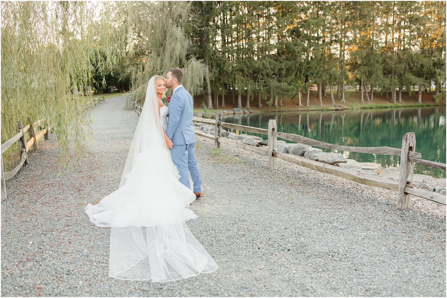 bride and groom walk down path at Windows on the Water at Frogbridge with veil trailing behind bride