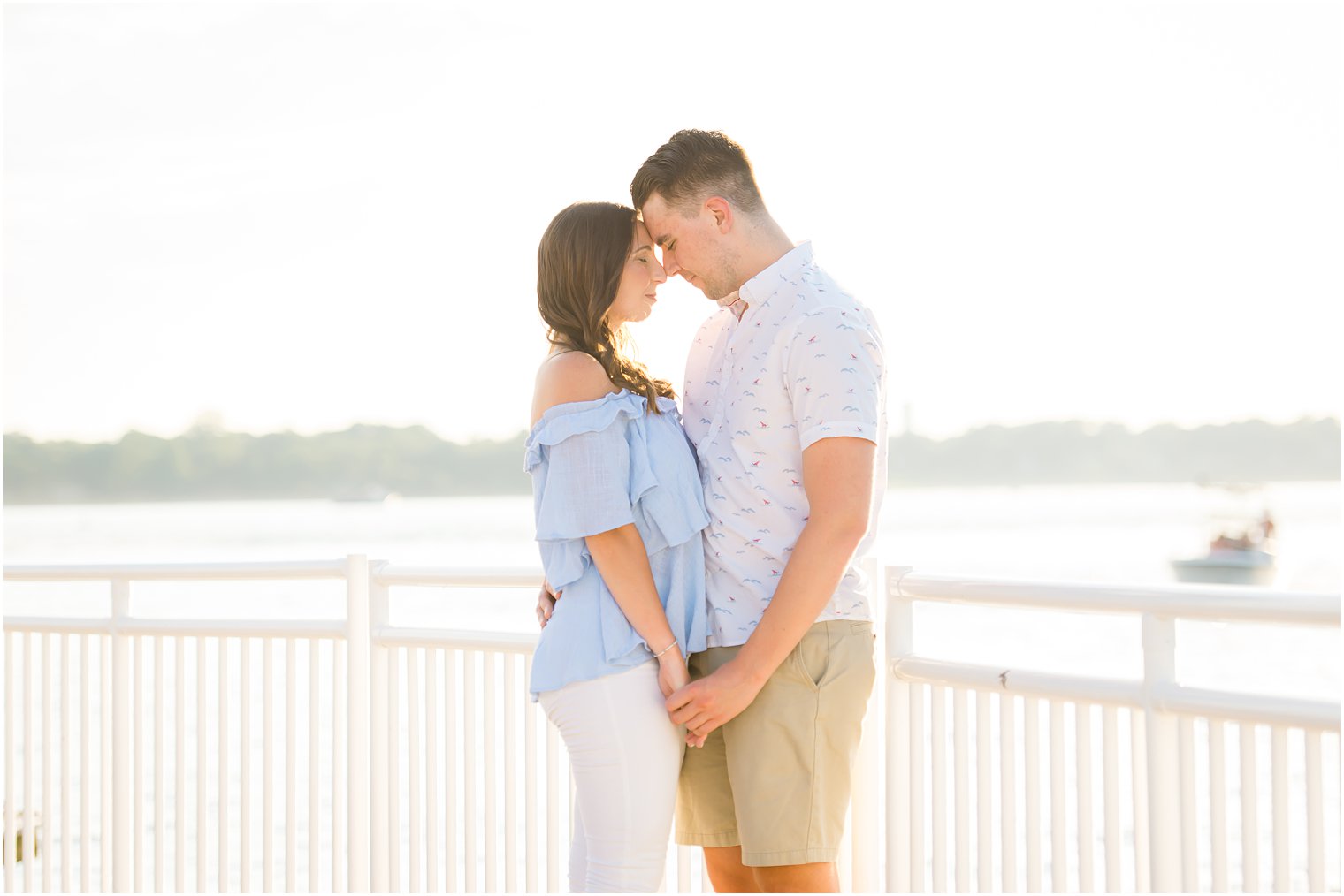 bride and groom stand touching noses on Belmar NJ pier