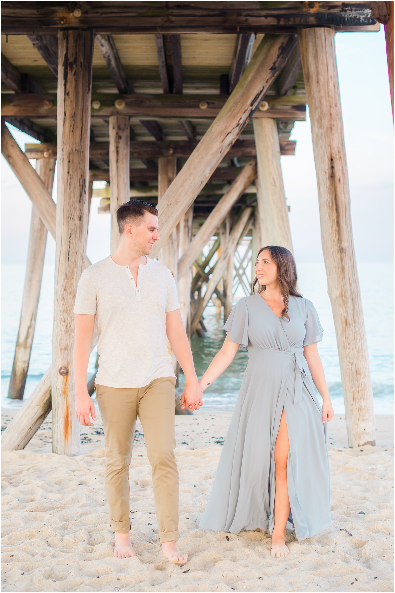 bride and groom walk under pier along Belmar NJ beach