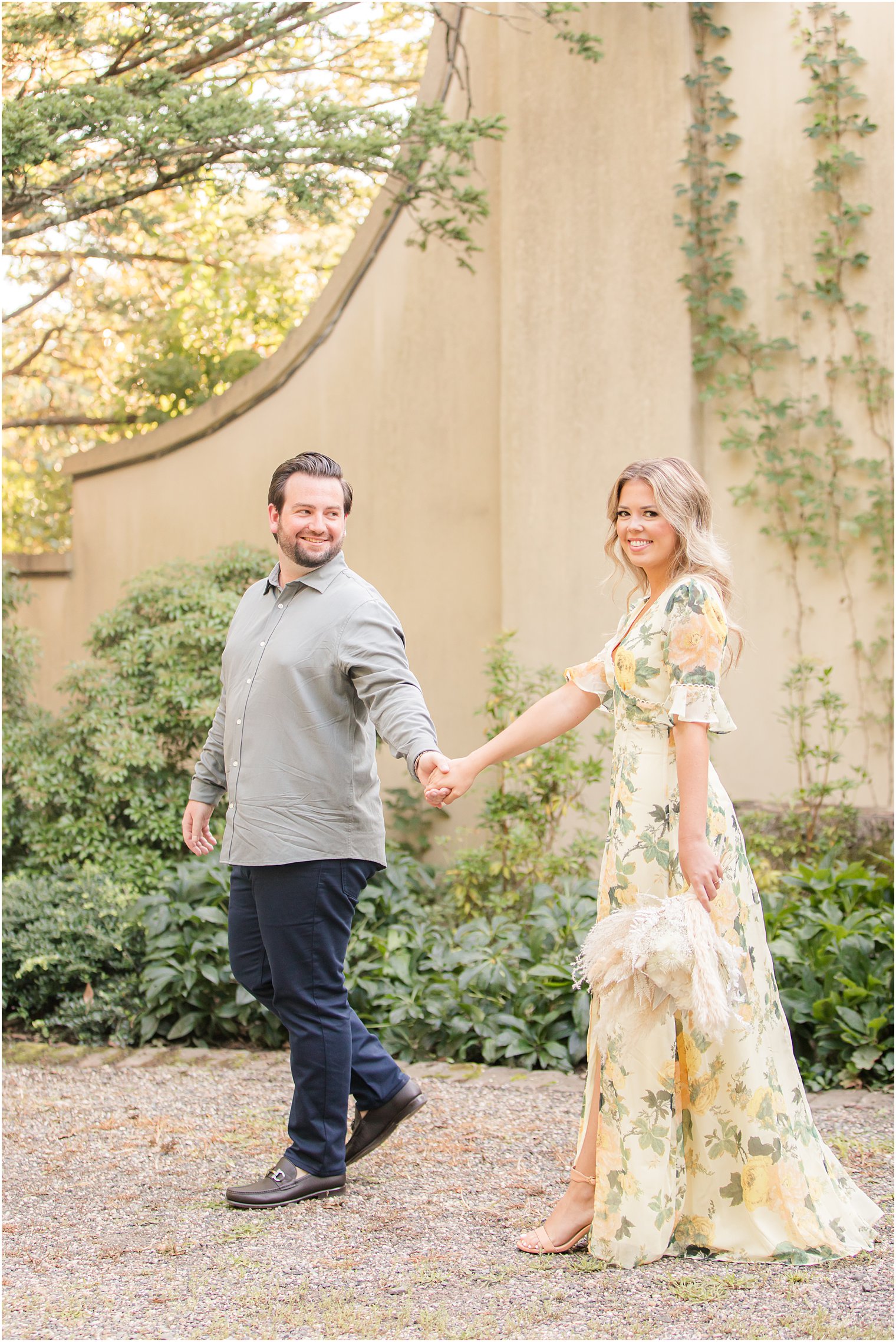 bride and groom hold hands walking through Cross Estate Gardens