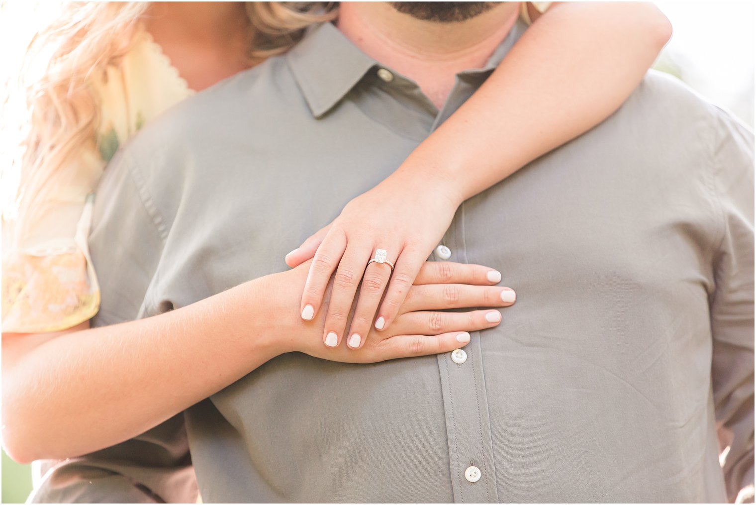 bride hugs groom from behind showing off engagement ring