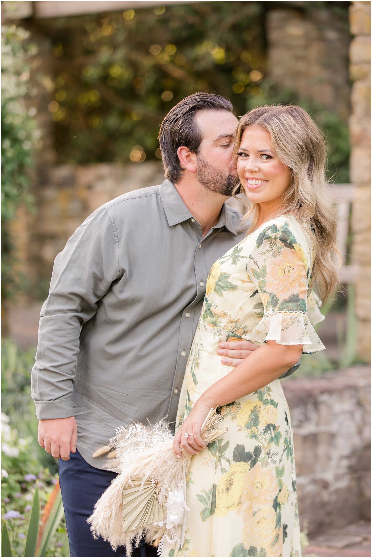 groom kisses bride while she holds bouquet of white flowers 