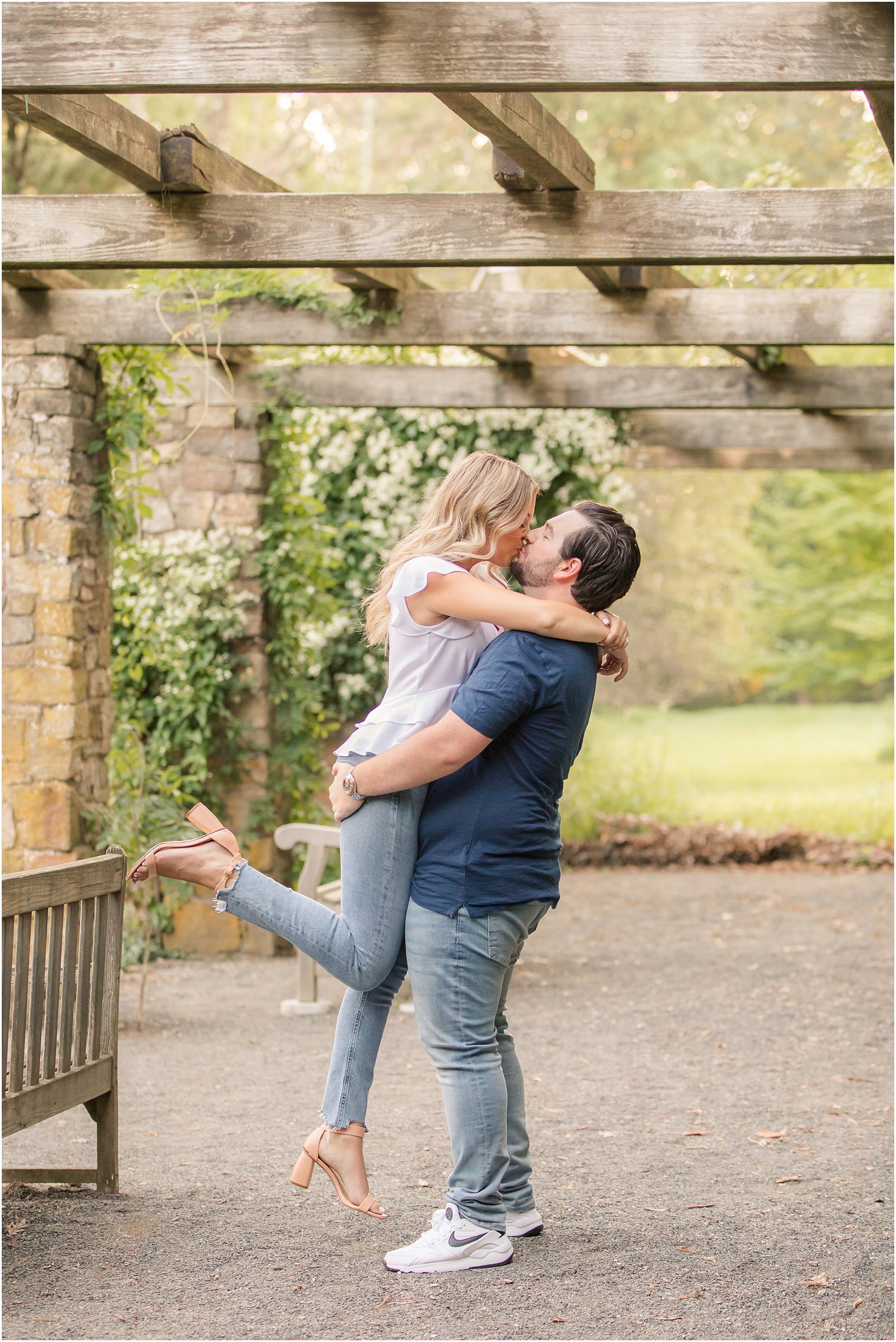 groom lifts bride under pergola at Cross Estate Gardens