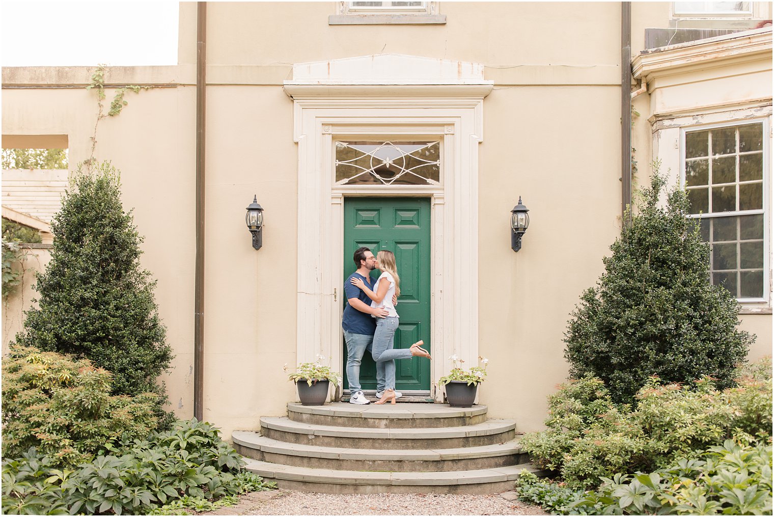 engaged couple kisses on steps of Cross Estate Gardens