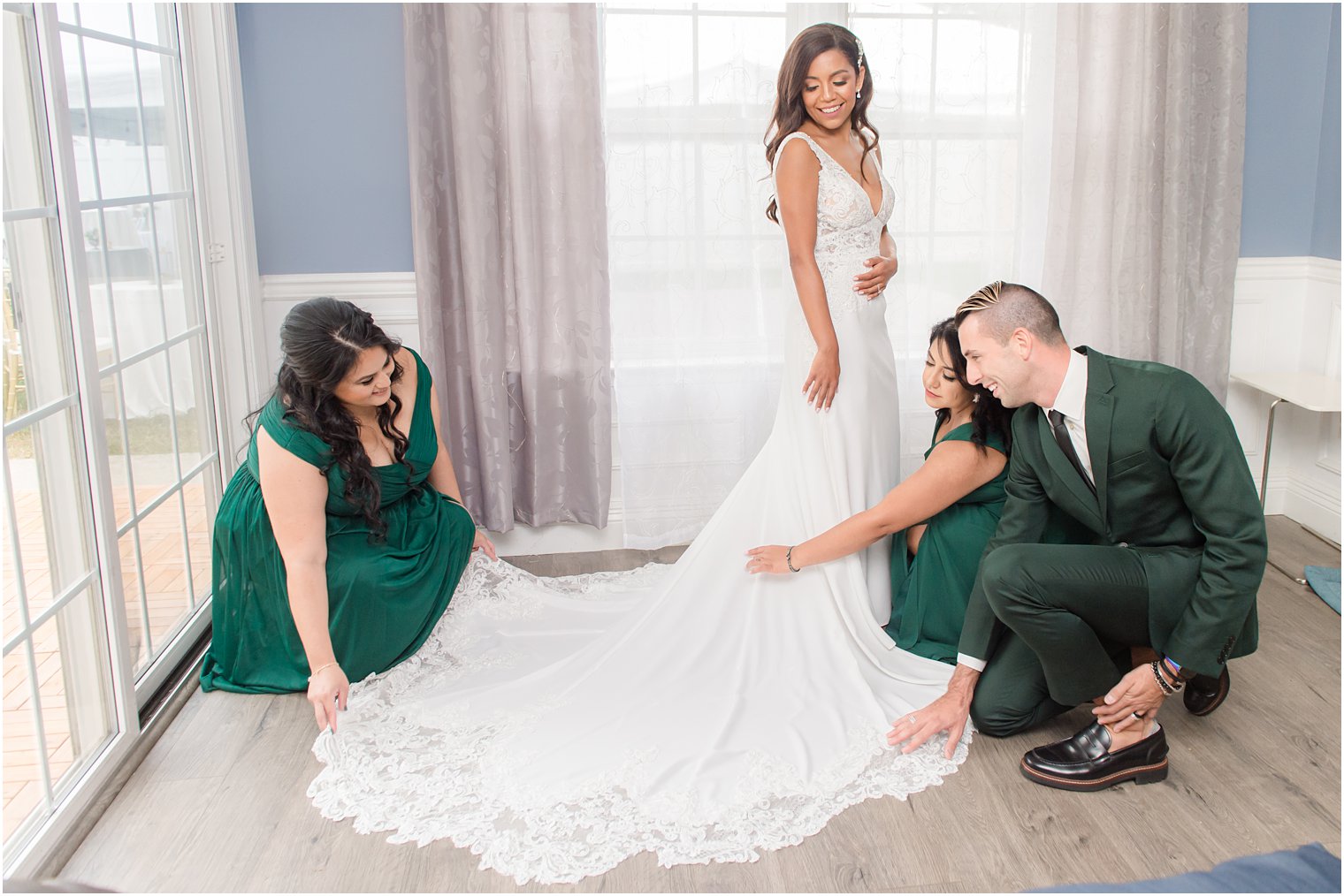 bridesmaids and man of honor help bride with train of dress