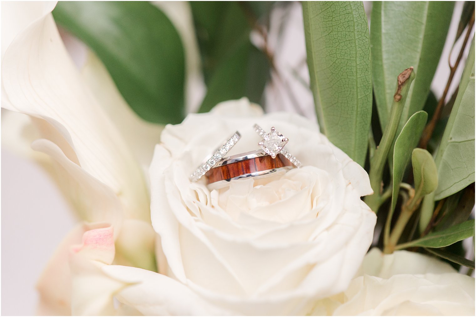 wedding rings rest on white rose