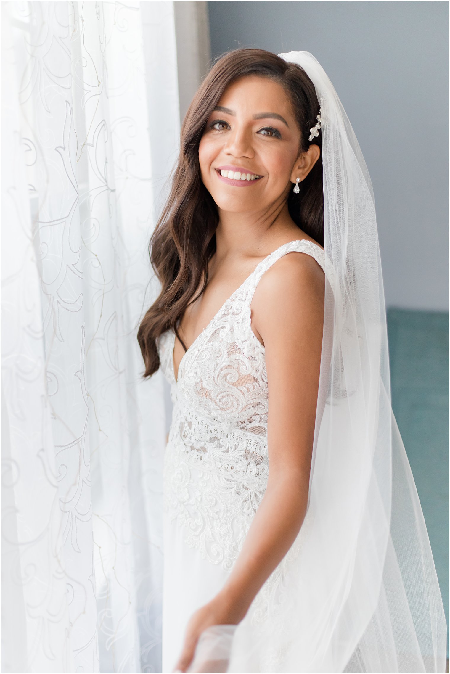 bride stands by window smiling before Toms River NJ wedding