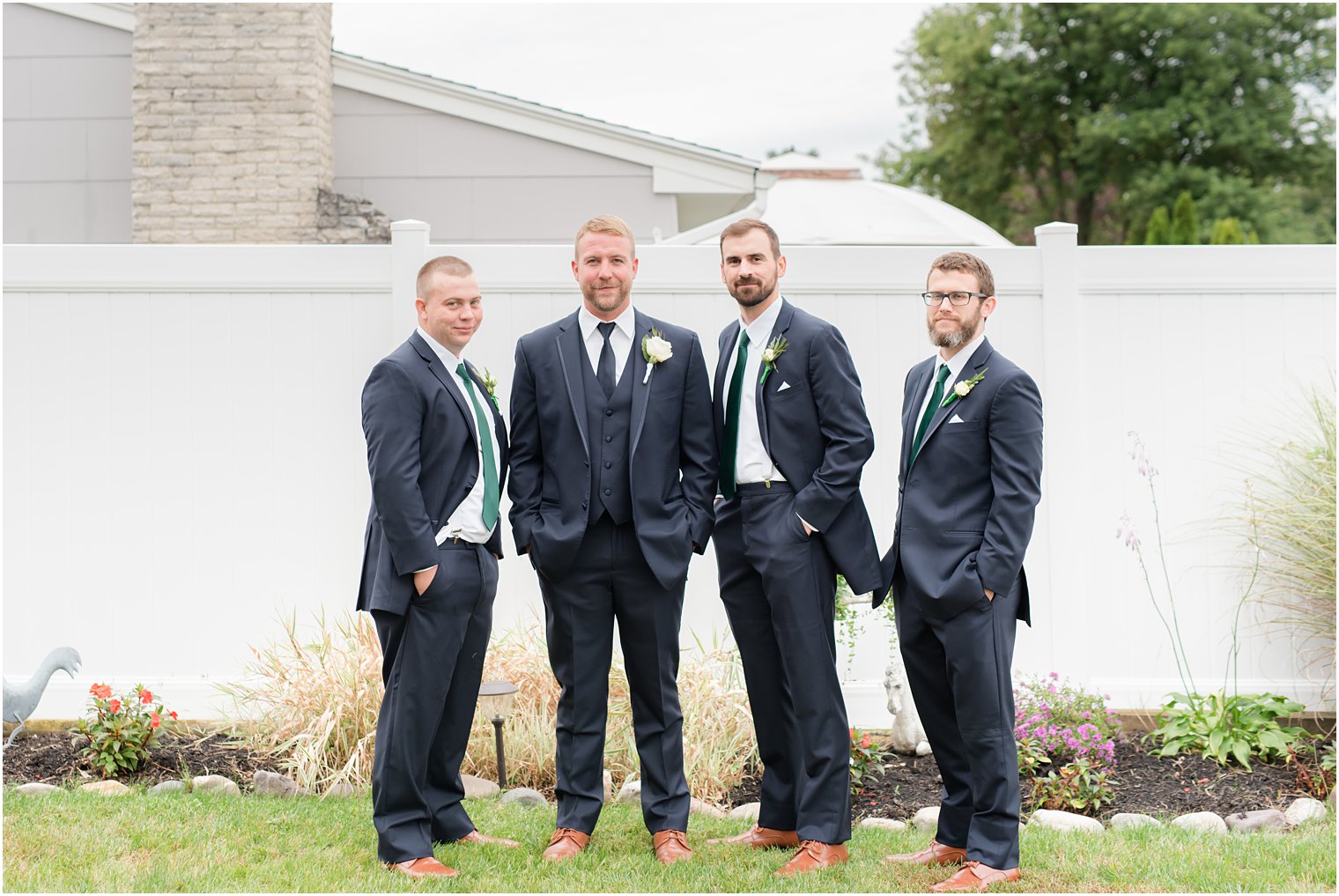 groom poses with groomsmen in backyard before NJ wedding