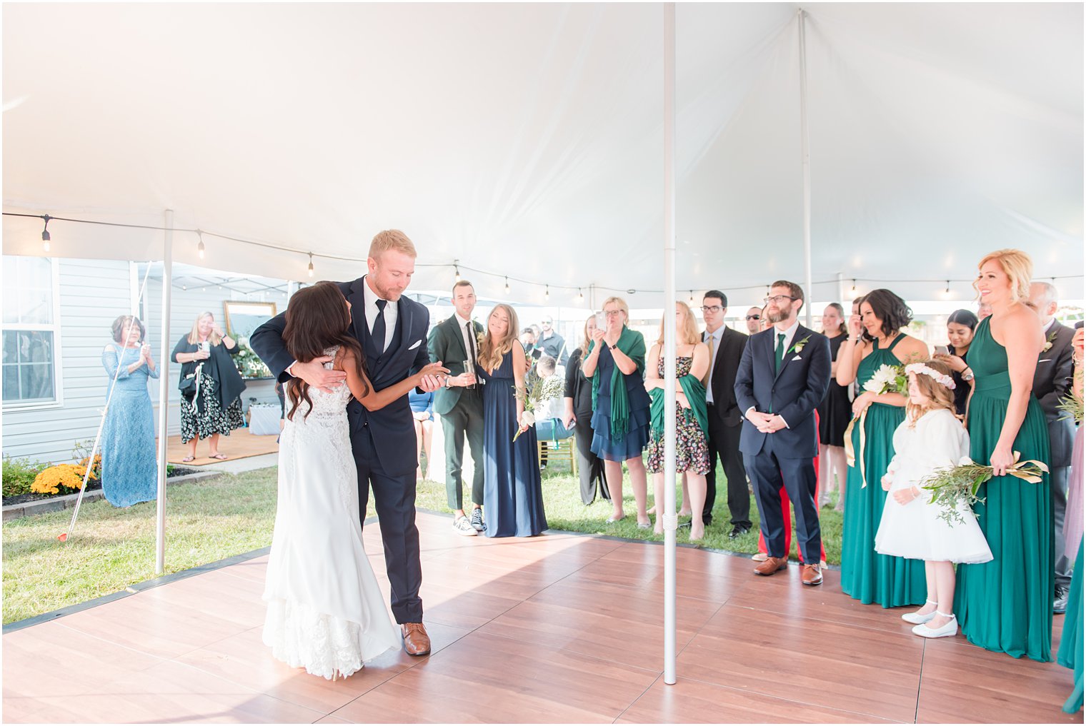 bride and groom dance during tented wedding reception in backyard