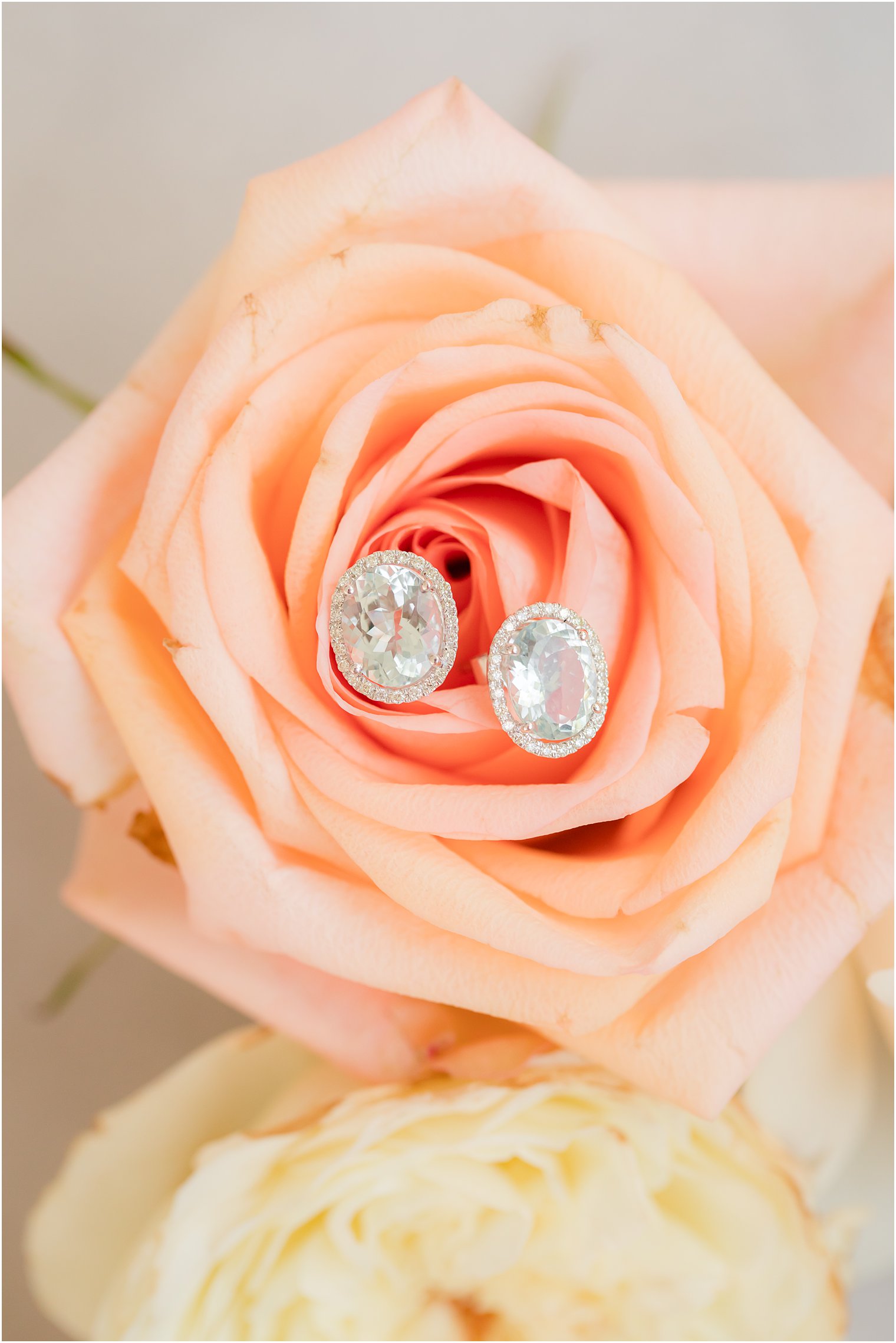 diamond earrings rest on peach rose before fall wedding