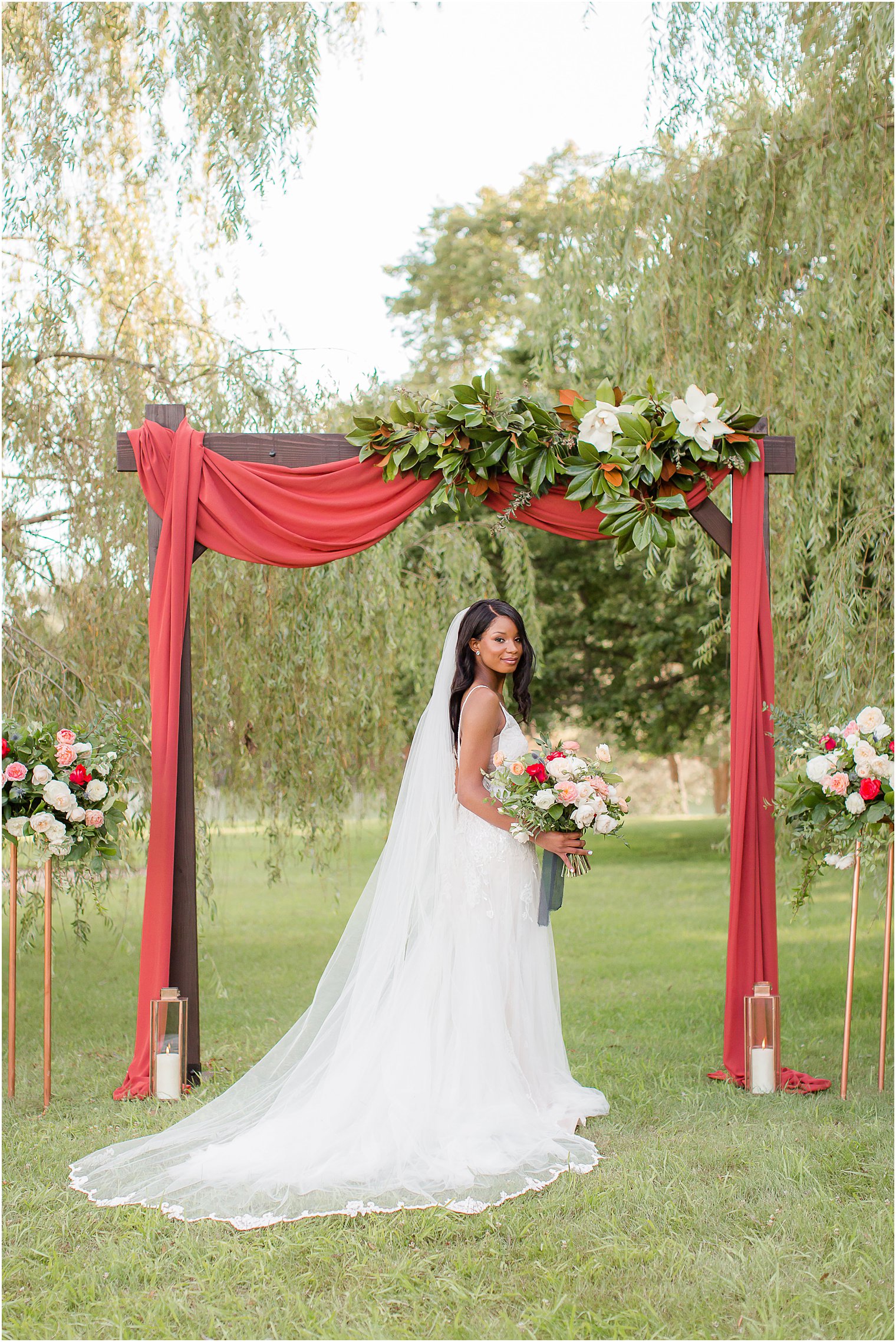 bride holds bouquet of ivory and pink flowers under canopy