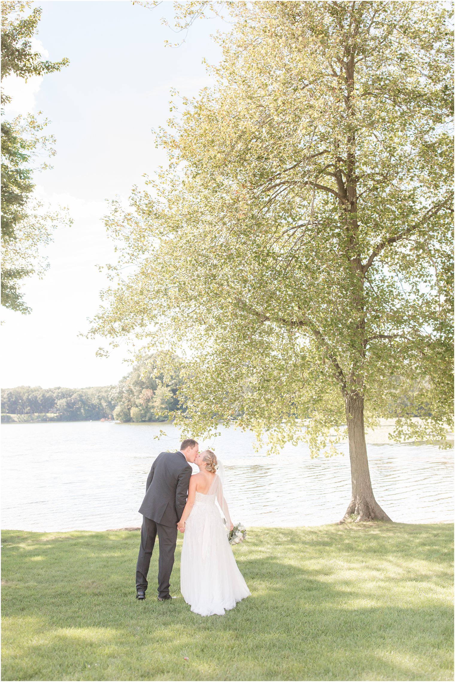 bride and groom kiss by lake at Indian Trail Club