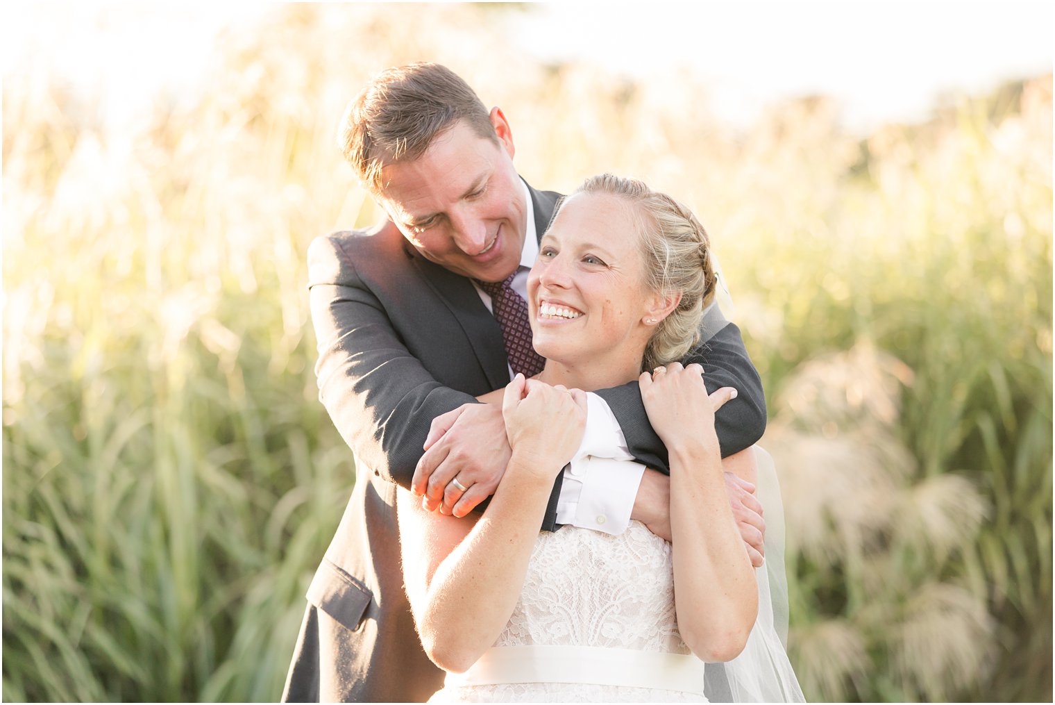 groom hugs bride from behind and smiles during NJ wedding photos