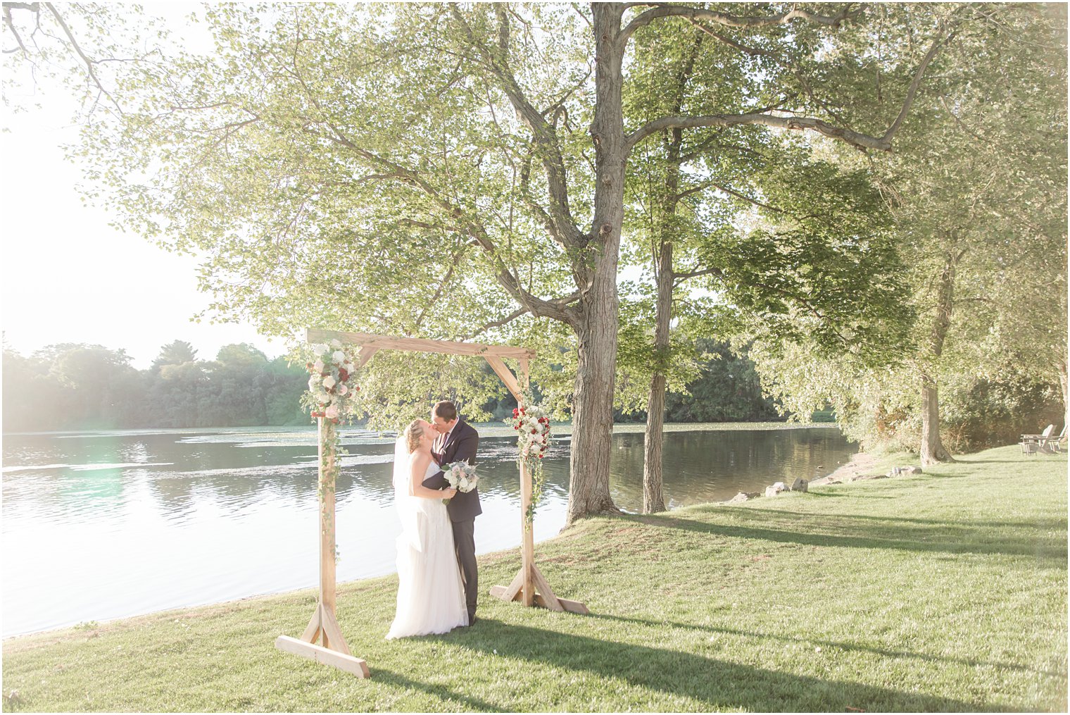 bride and groom kiss under wooden arbor at Indian Trail Club