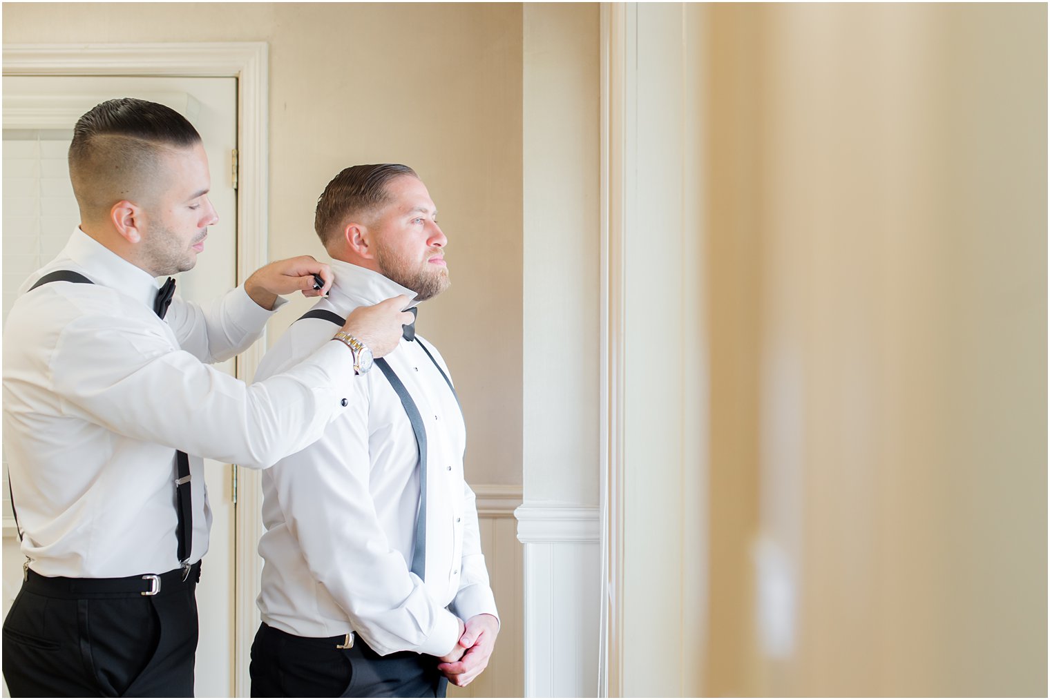 groomsman adjusts collar for NJ groom on wedding morning