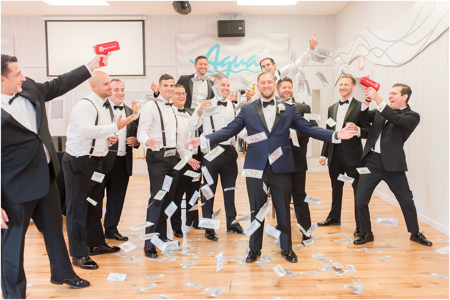 groomsmen shoot money gun at groom before wedding