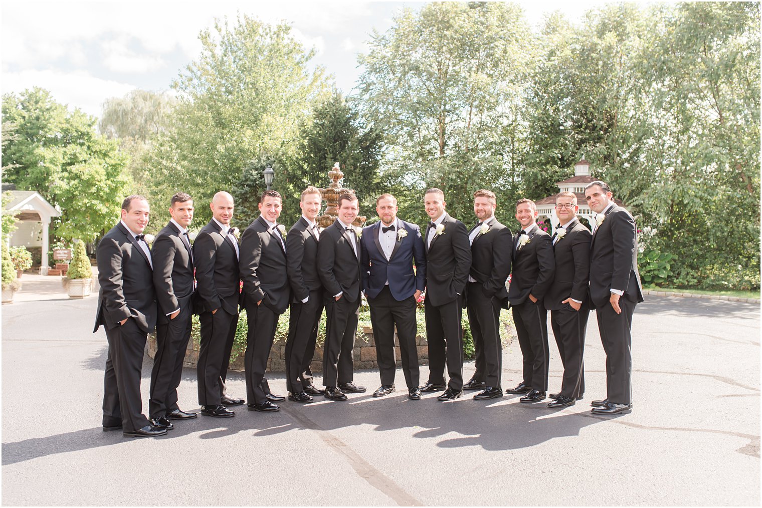groom poses with 10 groomsmen at Windows on the Water at Frogbridge