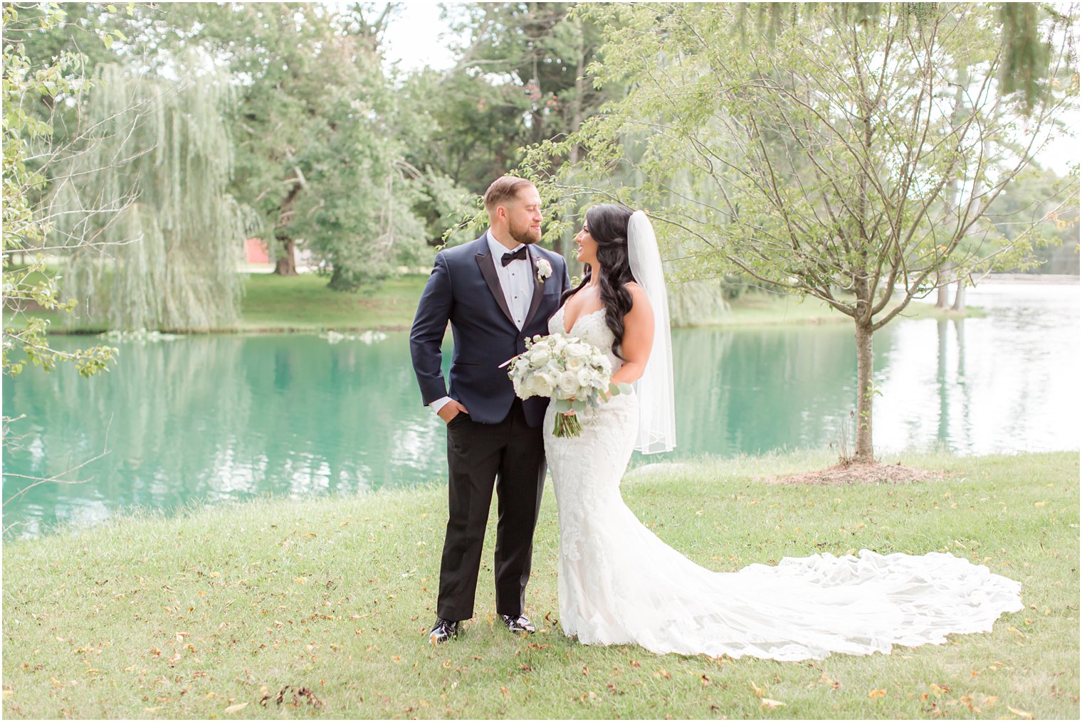 newlyweds pose by lake at Windows on the Water at Frogbridge