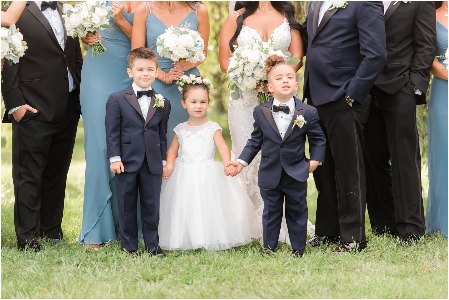 ring bearers hold flower girl's hand during wedding party photos