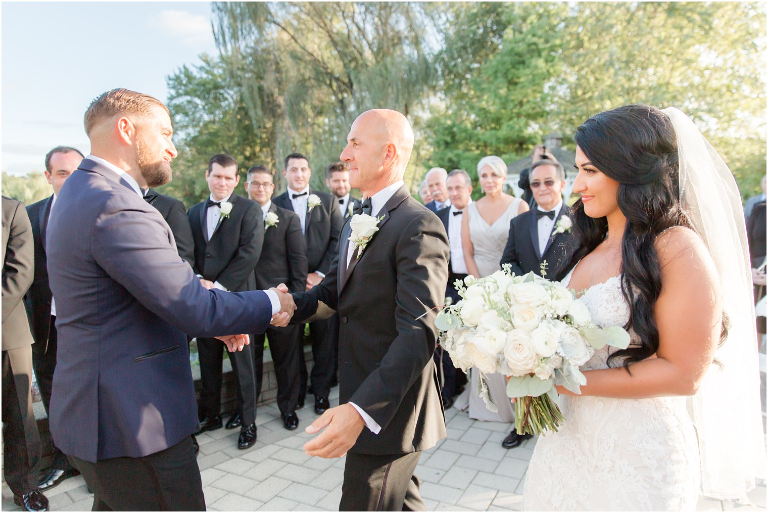 dad gives bride away during wedding ceremony and shakes groom's hand