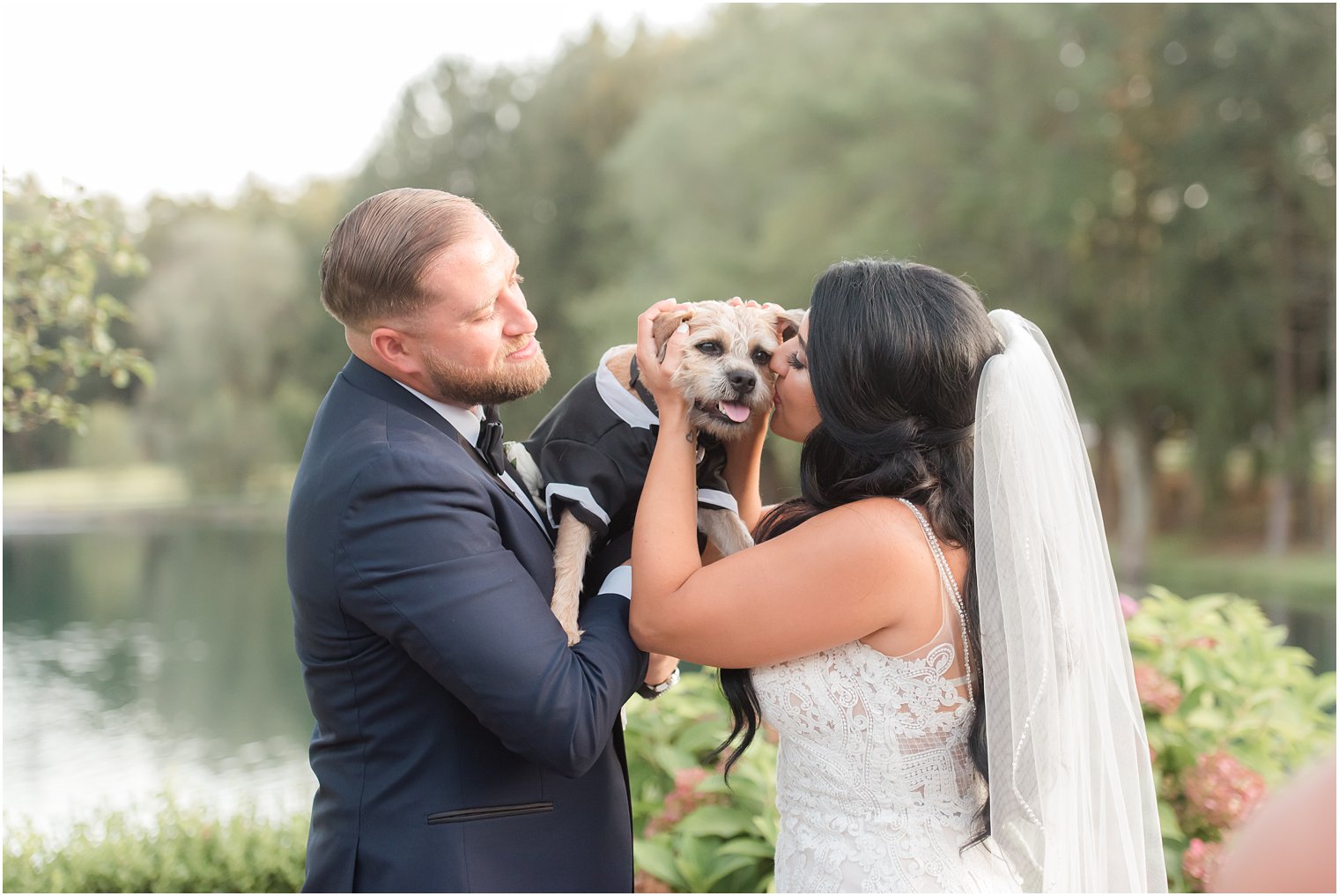 bride and groom play with dog on wedding day