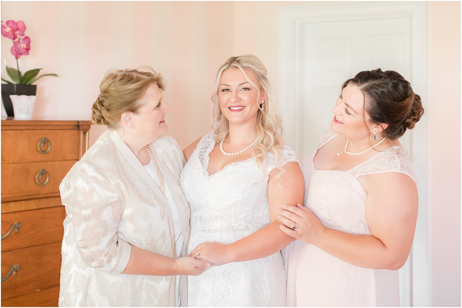 bride poses with mom and sister during prep for NJ wedding