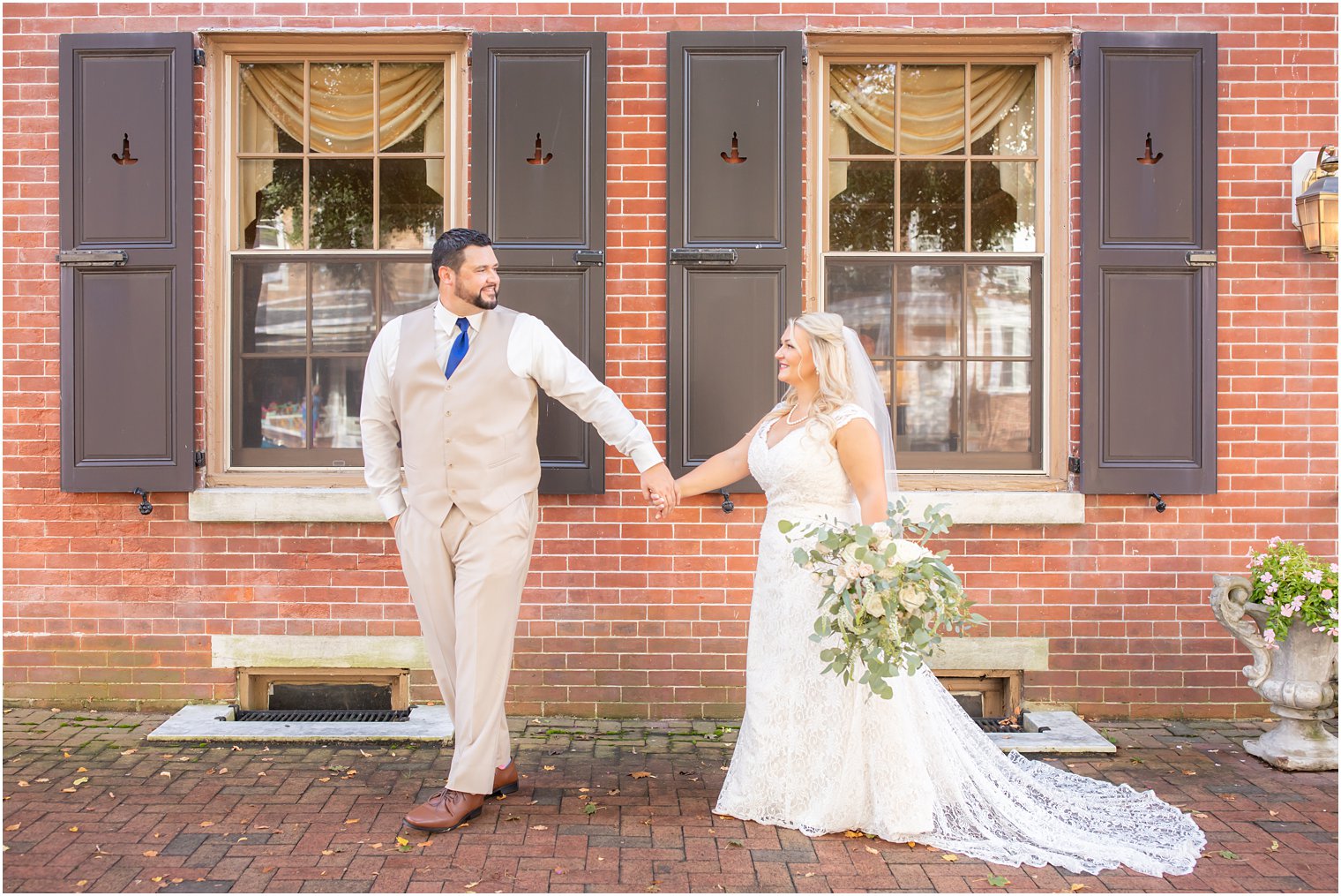 bride and groom hold hands walking down sidewalk by The Lily Inn