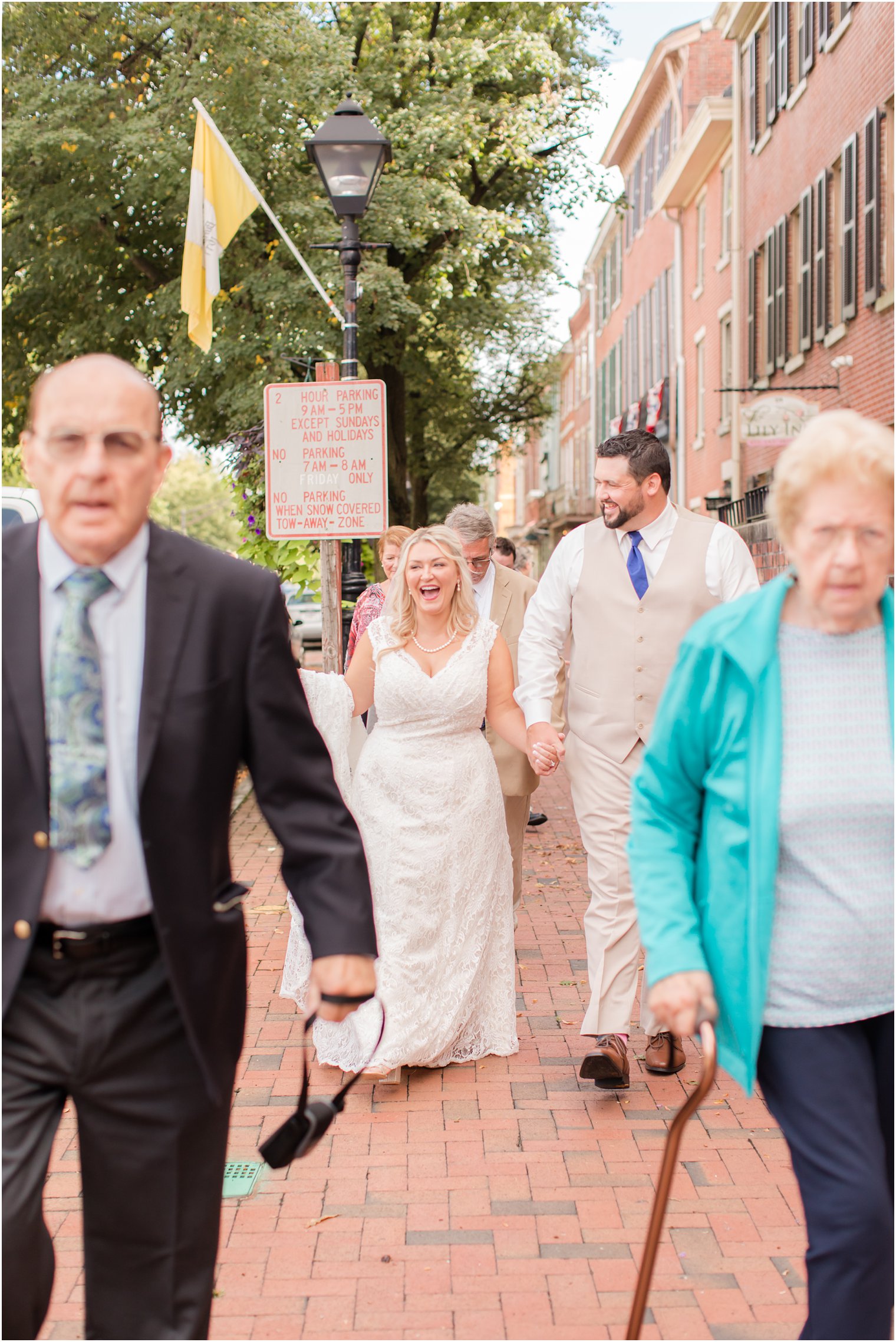 bride and groom walk down the street with family in New Jersey