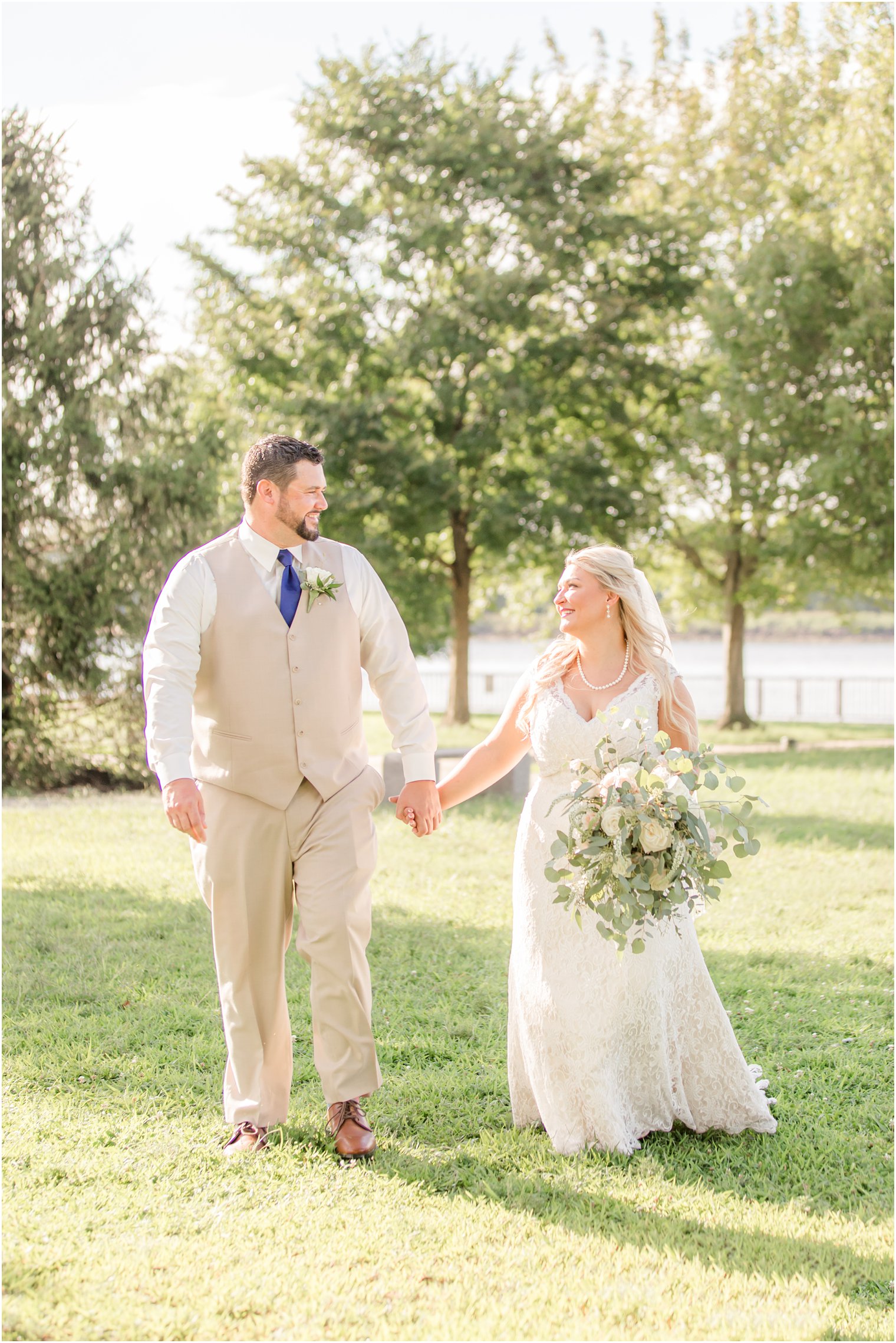 bride and groom walk holding hands and smiling at each other in Burlington NJ