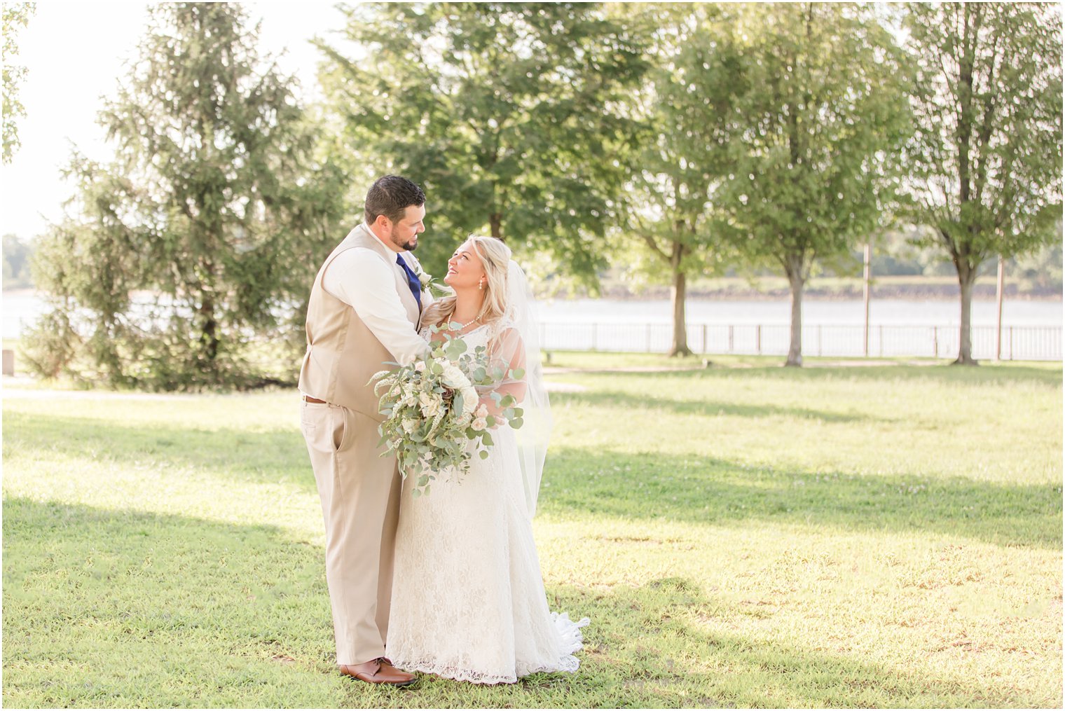 bride and groom hug while smiling at each other on wedding day