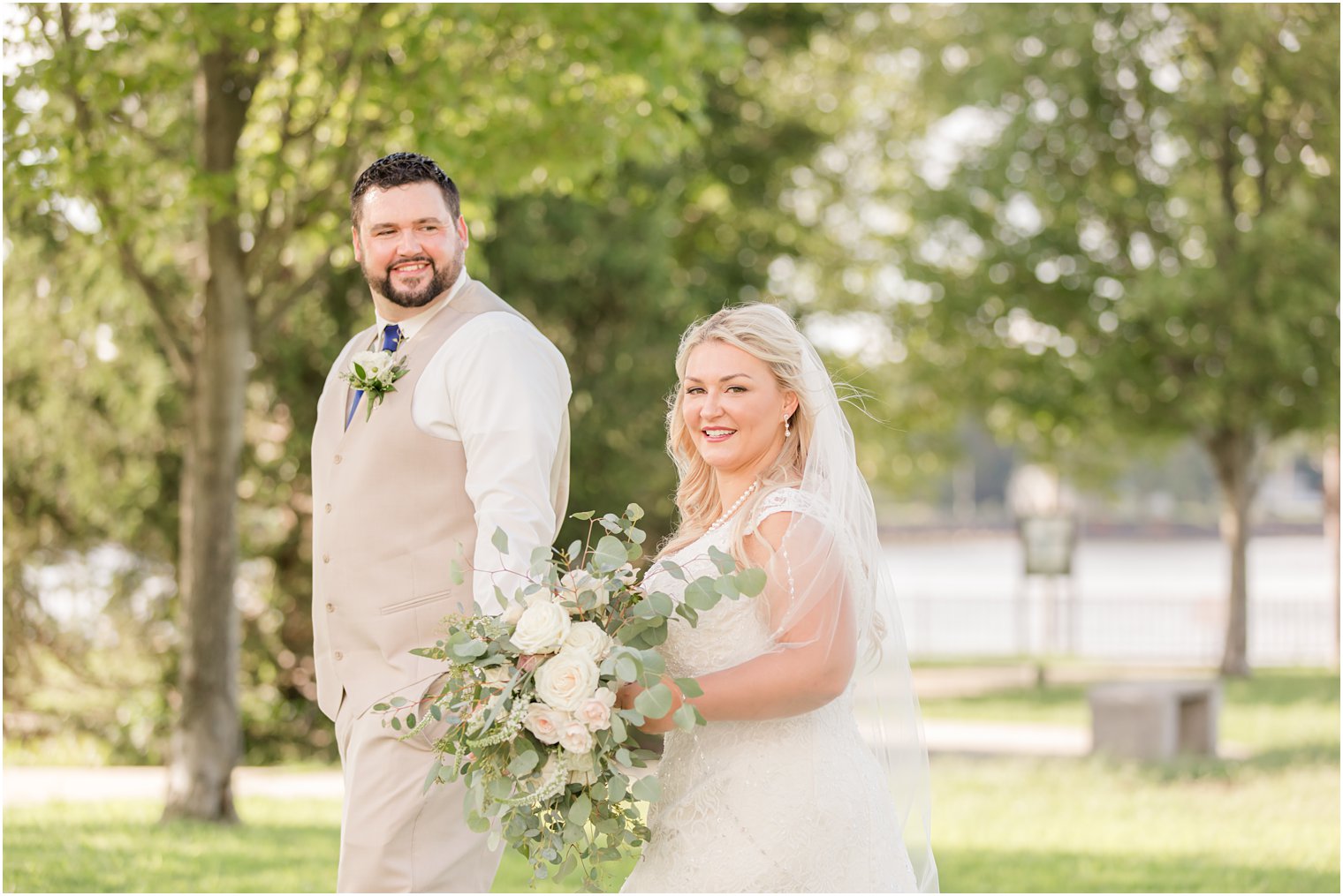 groom leads bride through park while looking back at her during NJ wedding day