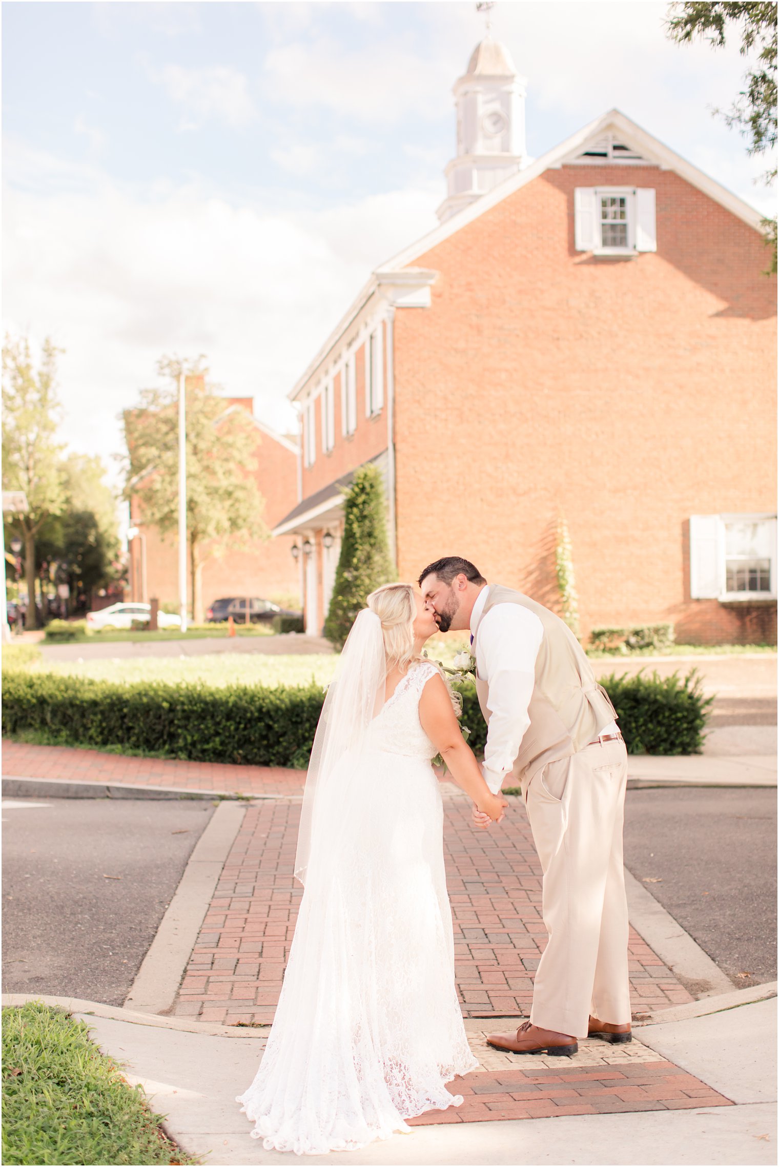 bride and groom kiss on sidewalk near The Lily Inn
