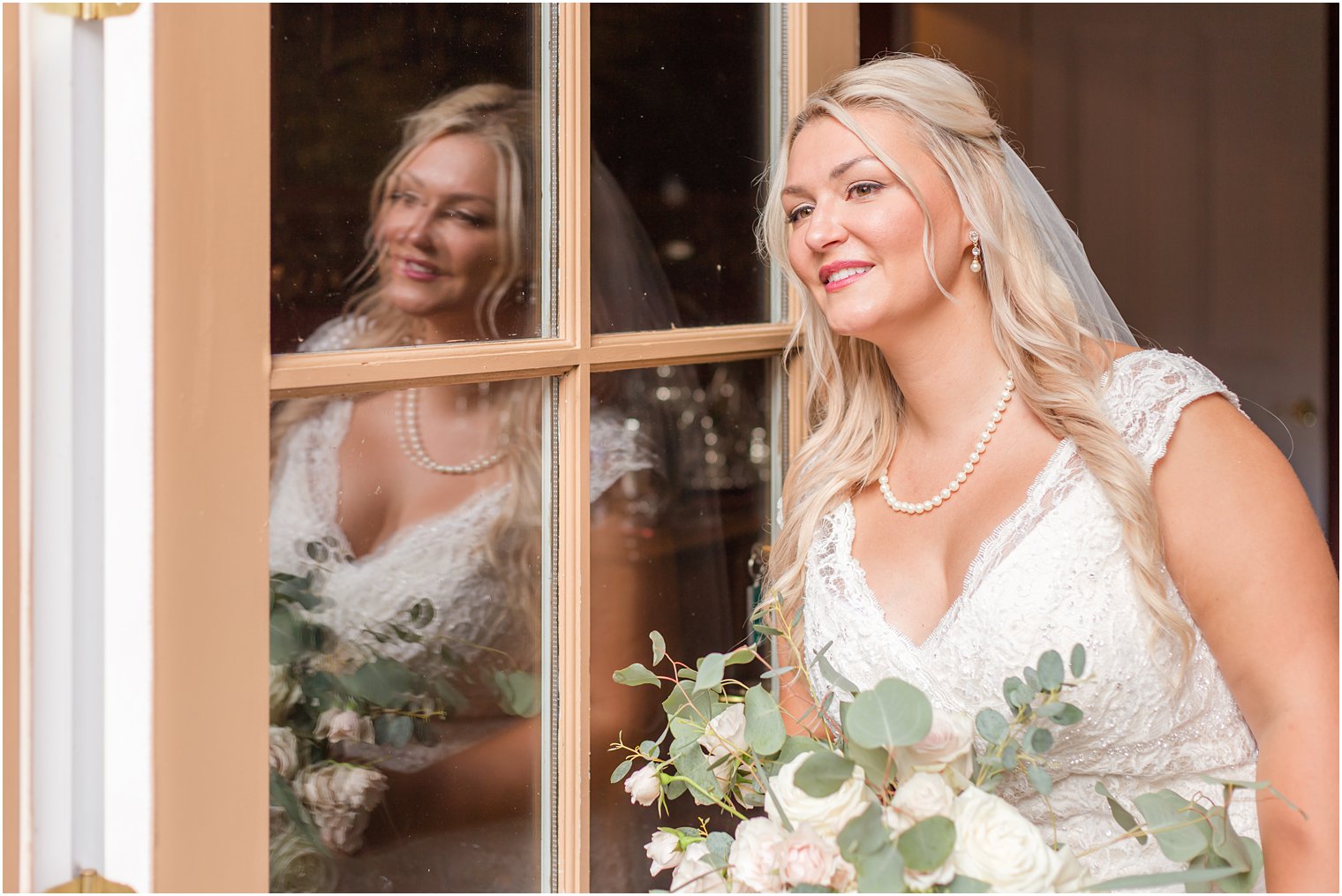 bride looks out the window of the Lily Inn in Burlington NJ before wedding ceremony