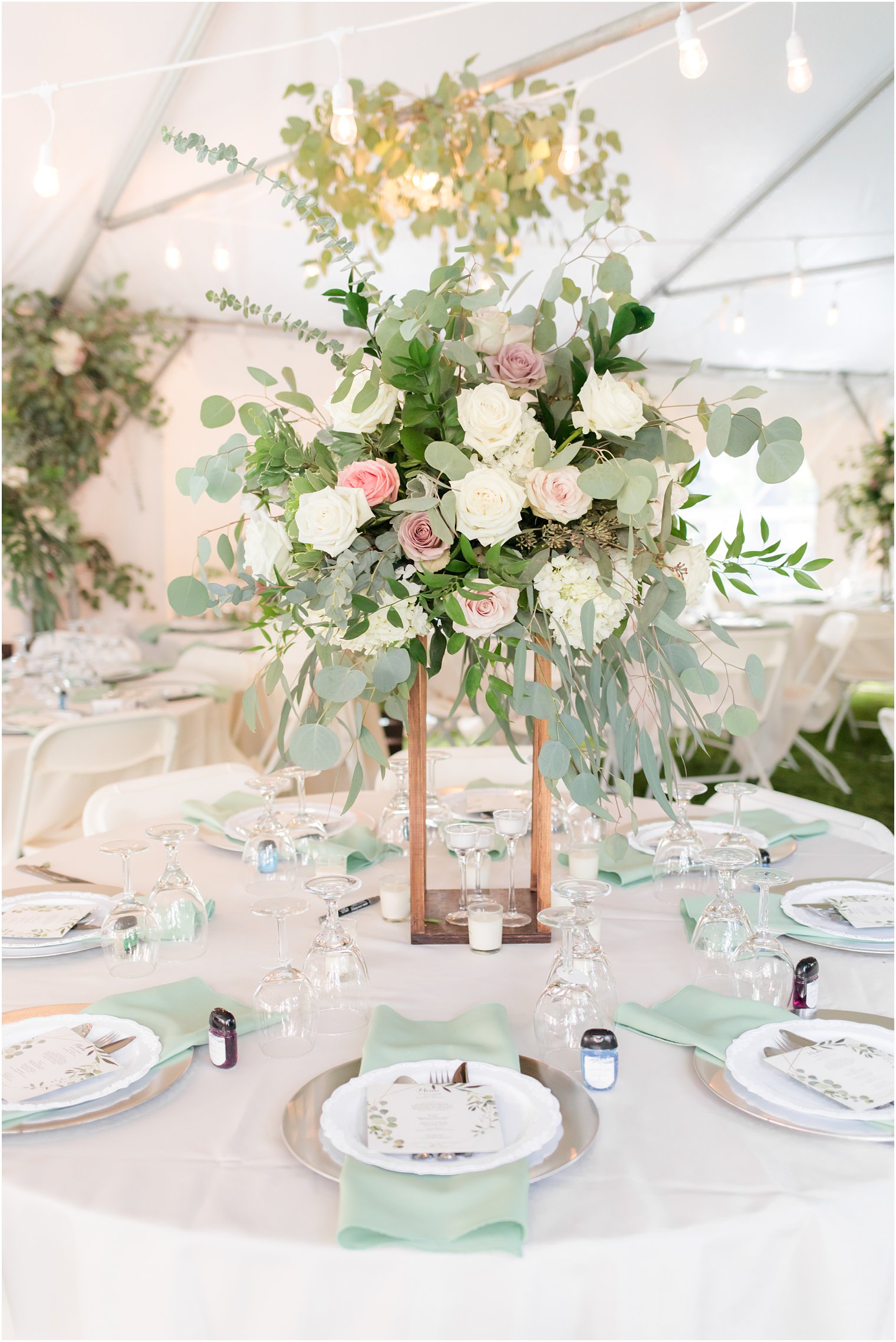 tall flower centerpieces with mint green accents during tented reception at the Lily Inn