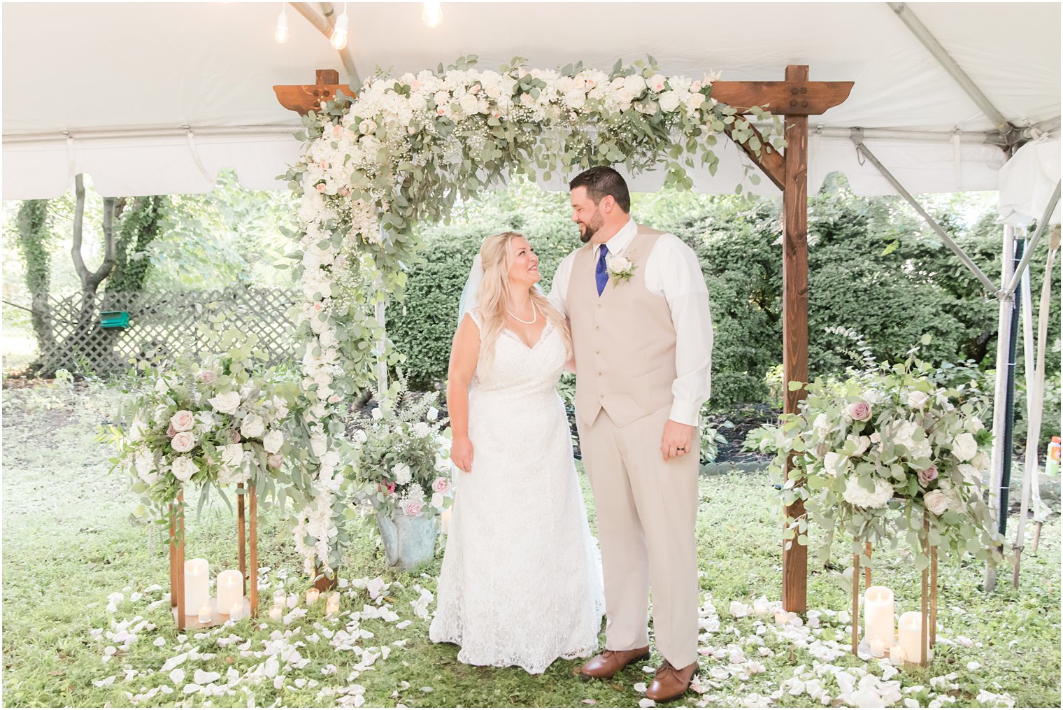 newlyweds smile under flower arbor at The Lily Inn