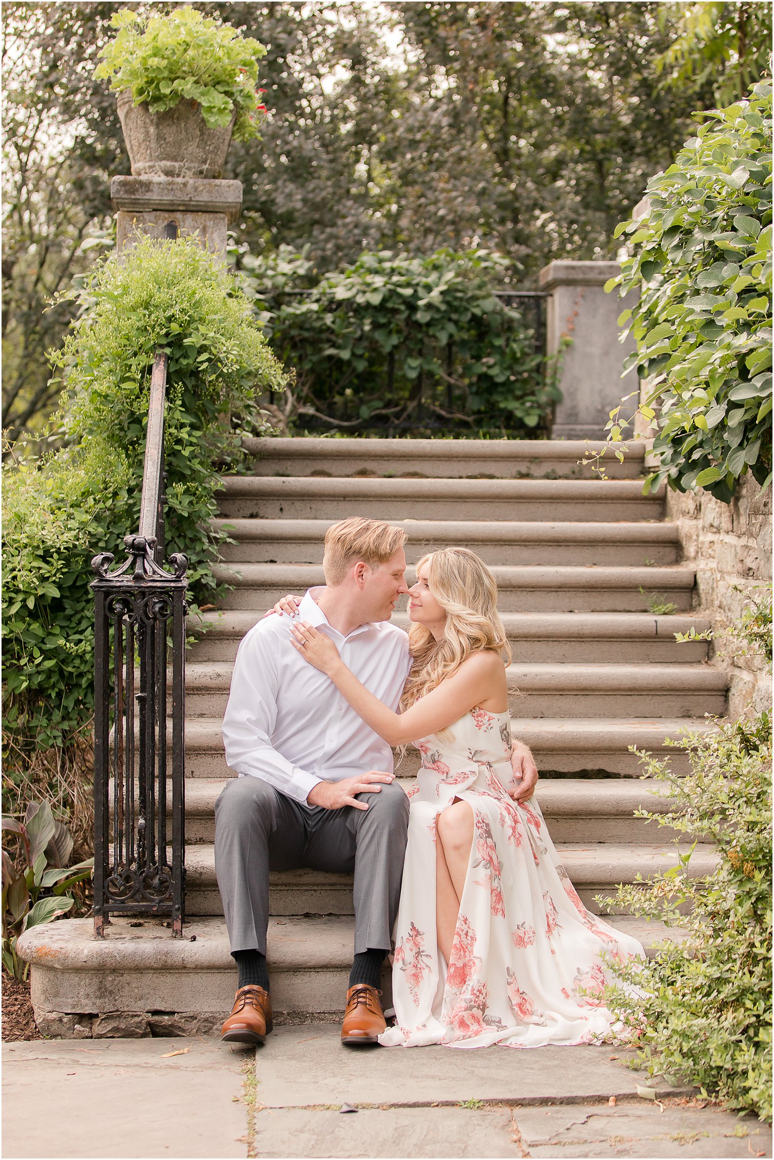 bride and groom sit on steps at Skylands Manor during engagement photos