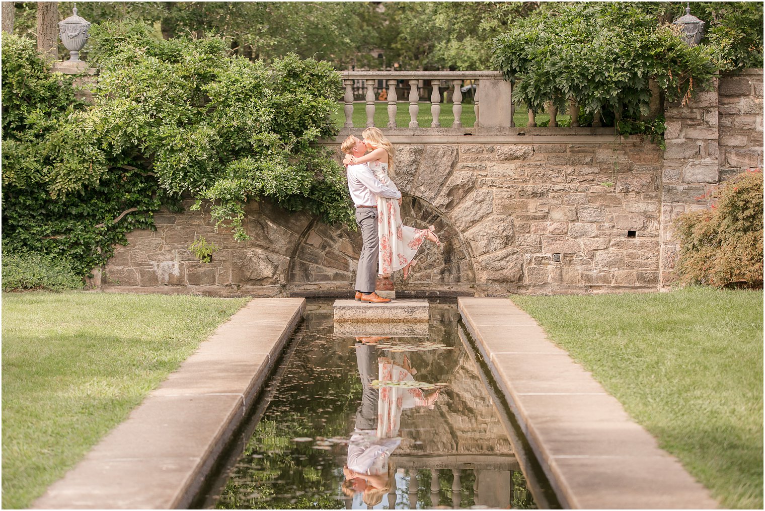 groom lifts bride during NJ engagement portraits by water