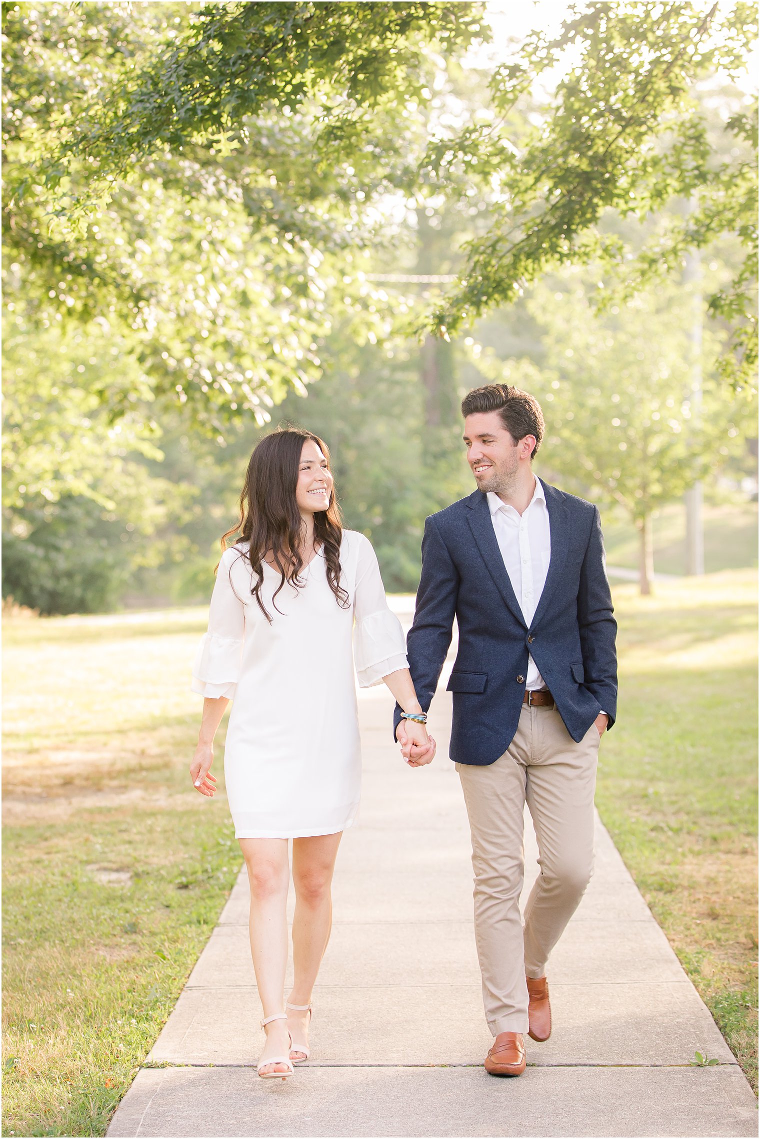 bride and groom hold hands walking through Spring Lake park