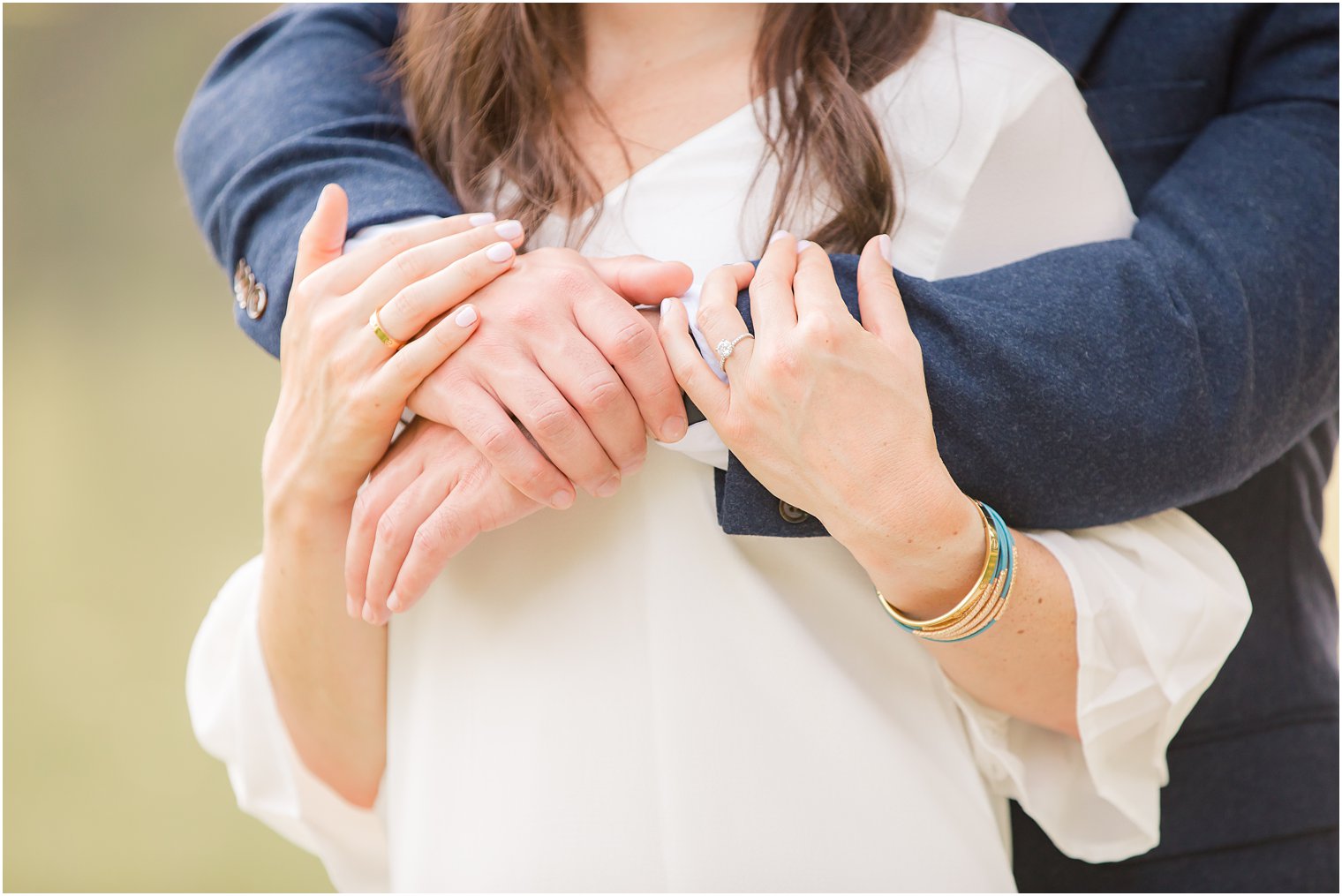 groom holds bride from behind and she holds his hands during Spring Lake NJ Engagement session