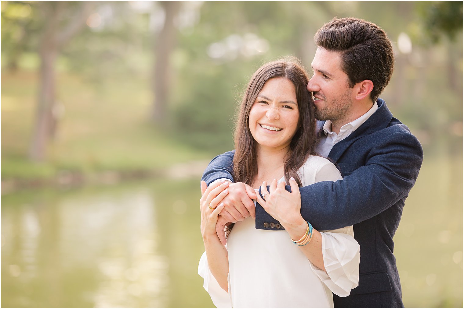 engaged couple laughs while posing by the water in Spring Lake NJ