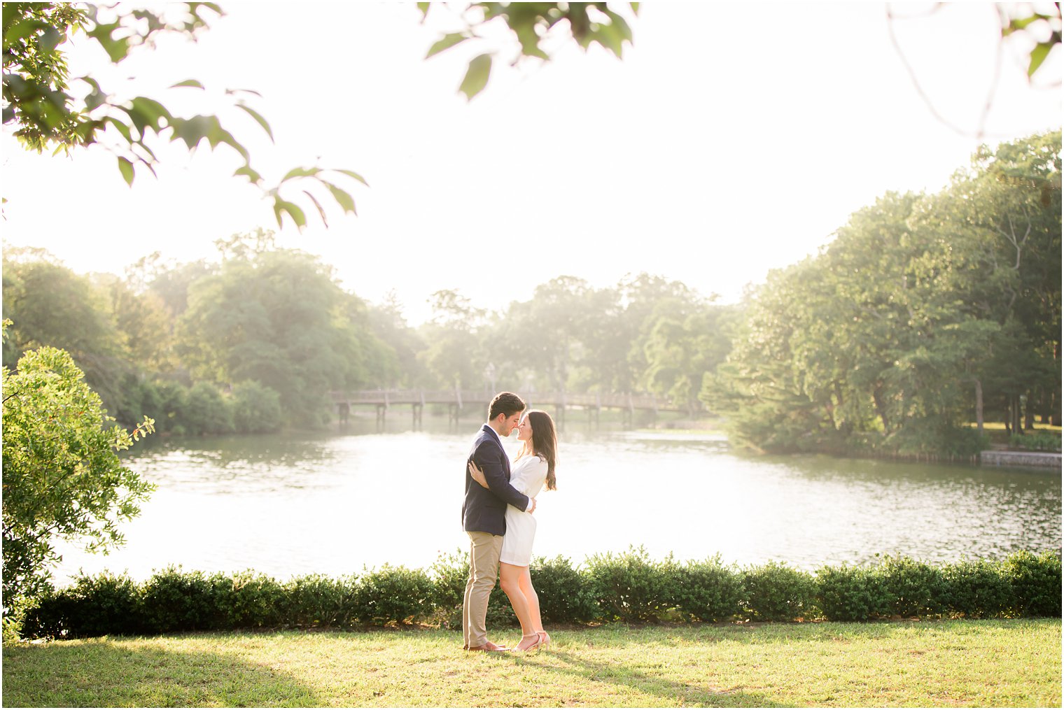 engaged couple stands touching noses by lake in New Jersey